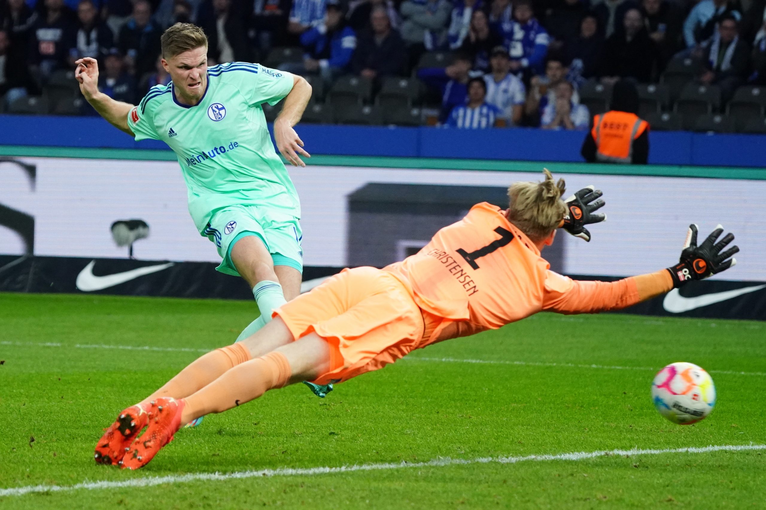 epa10261134 Schalke’s Marius Buelter (L) in action against Hertha’s goalkeeper Oliver Christensen during the German Bundesliga soccer match between Hertha BSC and FC Schalke 04 in Berlin, Germany, 23 October 2022.  EPA/CLEMENS BILAN (ATTENTION: The DFL regulations prohibit any use of photographs as image sequences and/or quasi-video.)