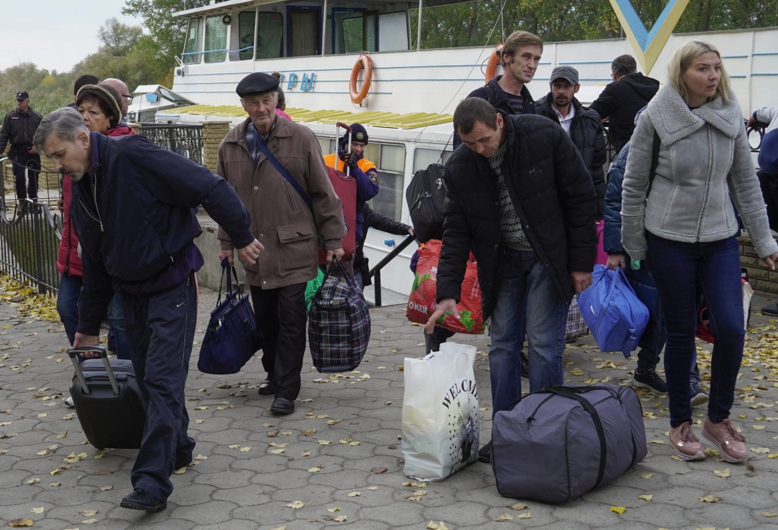 epa10265062 Kherson residents evacuated from Kherson carry luggage after their arrival to Oleshky, Kherson region, Ukraine, 25 October 2022. The authorities of the Kherson region announced the mass displacement of residents of several municipalities, including the city of Kherson, to the left bank of the Dnieper. According to the Acting Governor of the region Vladimir Saldo, this is necessary because of the increased frequency of attacks by the Armed Forces of Ukraine, as well as in connection with the threat of flooding of the territories due to the possible destruction of the dam of the Kakhovskaya hydroelectric power station. According to the deputy head of the regional administration Kirill Stremousov, about 32,000 people were transported to the other side of the Dnipro river.  EPA/STRINGER