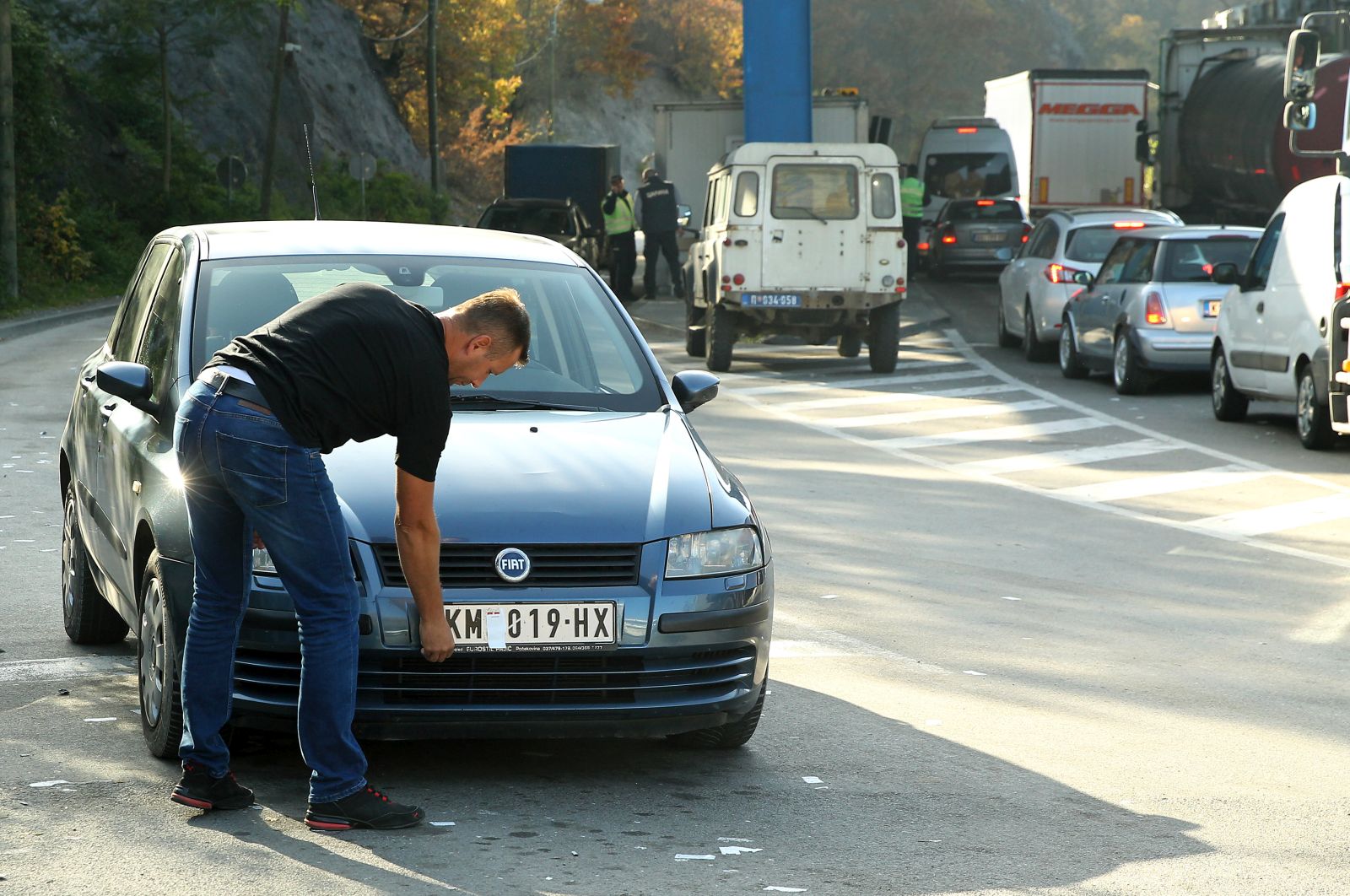 epa10279186 A motorist takes off stickers covering the national markings on his car license plates at the Jarinje border crossing between Kosovo and Serbia at Jarinje, Serbia, 01 November 2022. The Government of Kosovo will begin implementing a plan to eliminate the usage of Serbian car license plates. All owners of vehicles with Serbian number plates are warned and requested to visit any of the Vehicle Registration Centers and register their vehicles with RKS license plates. In the Serbian community of Kosovo, the RKS license plates are seen as unacceptable as they suggest the recognition of independence of the Republic of Kosovo.  EPA/DJORDJE SAVIC