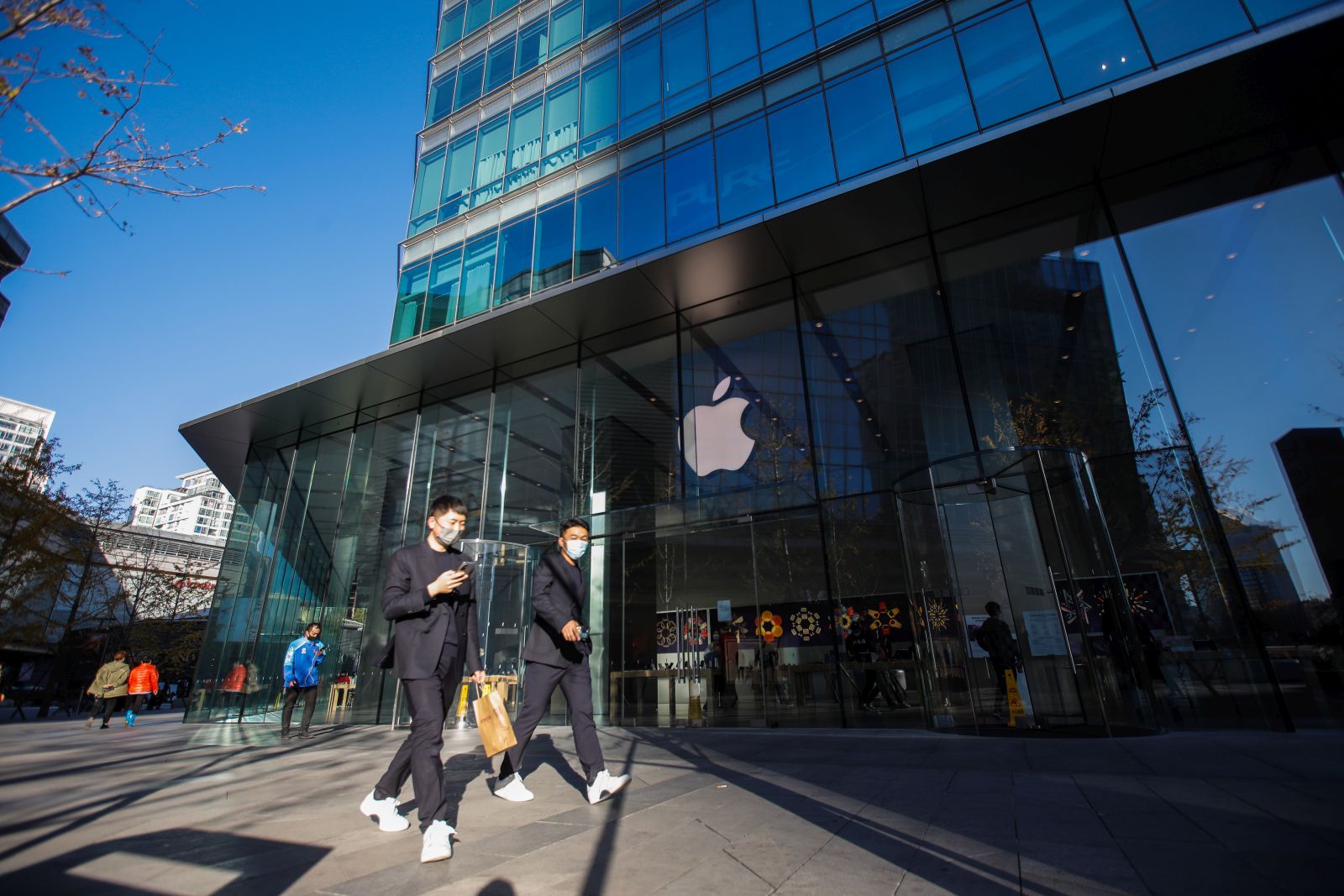 epa10291970 People wearing face masks walk past an Apple store at a mall in Beijing, China, 07 November 2022. China's Foxconn iPhone facotry in Zhengzhou was working to resume its production that had been hit by COVID-19 curbs, according to a company statement released on 07 November.  EPA/WU HAO