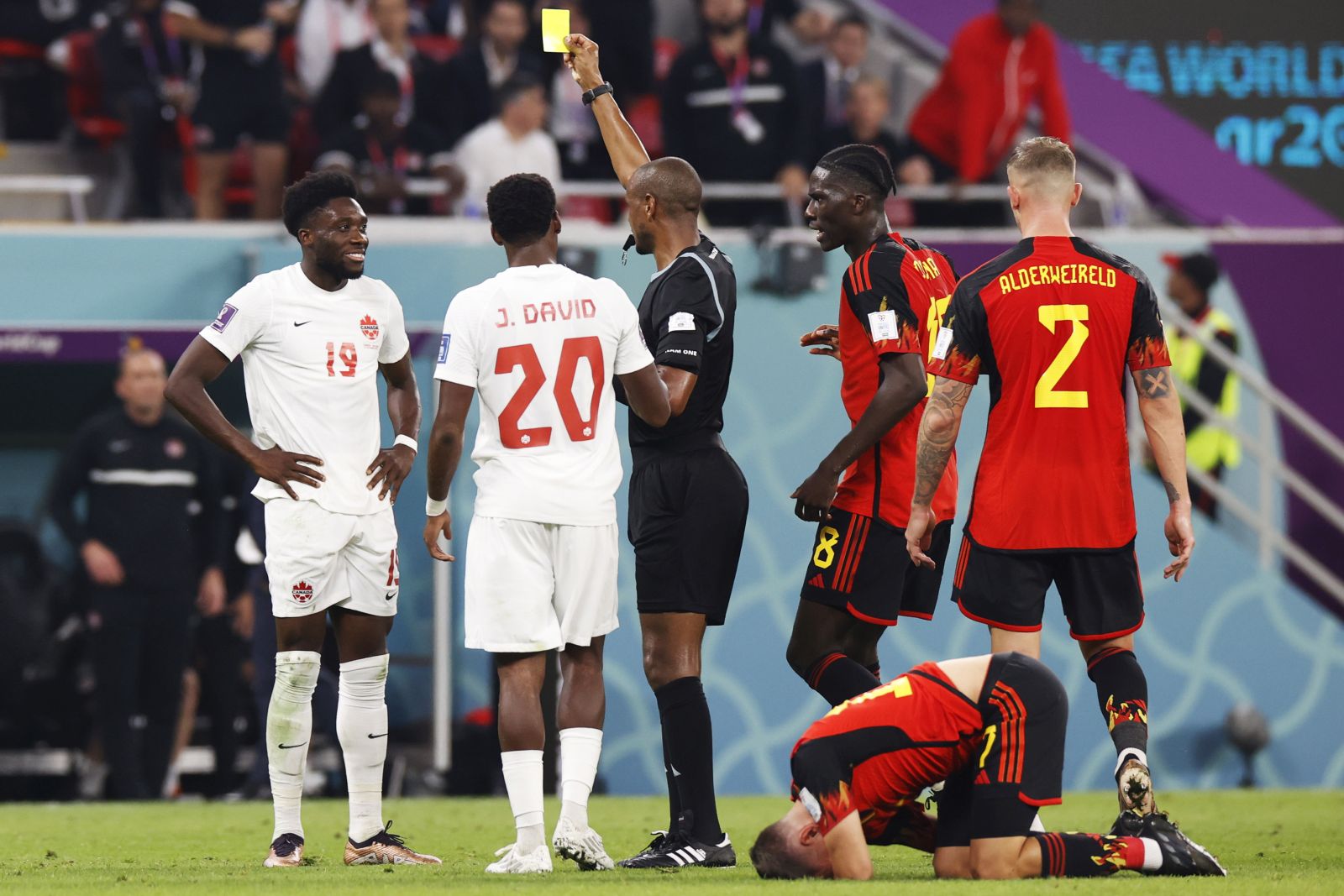 epa10323785 Referee Janny Sikazwe (C) shows the yellow card to Alphonso Davies of Canada (L) during the FIFA World Cup 2022 group F soccer match between Belgium and Canada at Ahmad bin Ali Stadium in Doha, Qatar, 23 November 2022.  EPA/Rungroj Yongrit
