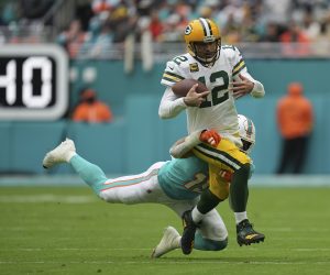 Green Bay Packers quarterback Aaron Rodgers (12) runs through a tackle by Miami Dolphins linebacker Jaelan Phillips (15) as he runs with the ball during the first half of an NFL football game, Sunday, Dec. 25, 2022, in Miami Gardens, Fla. (AP Photo/Jim Rassol)