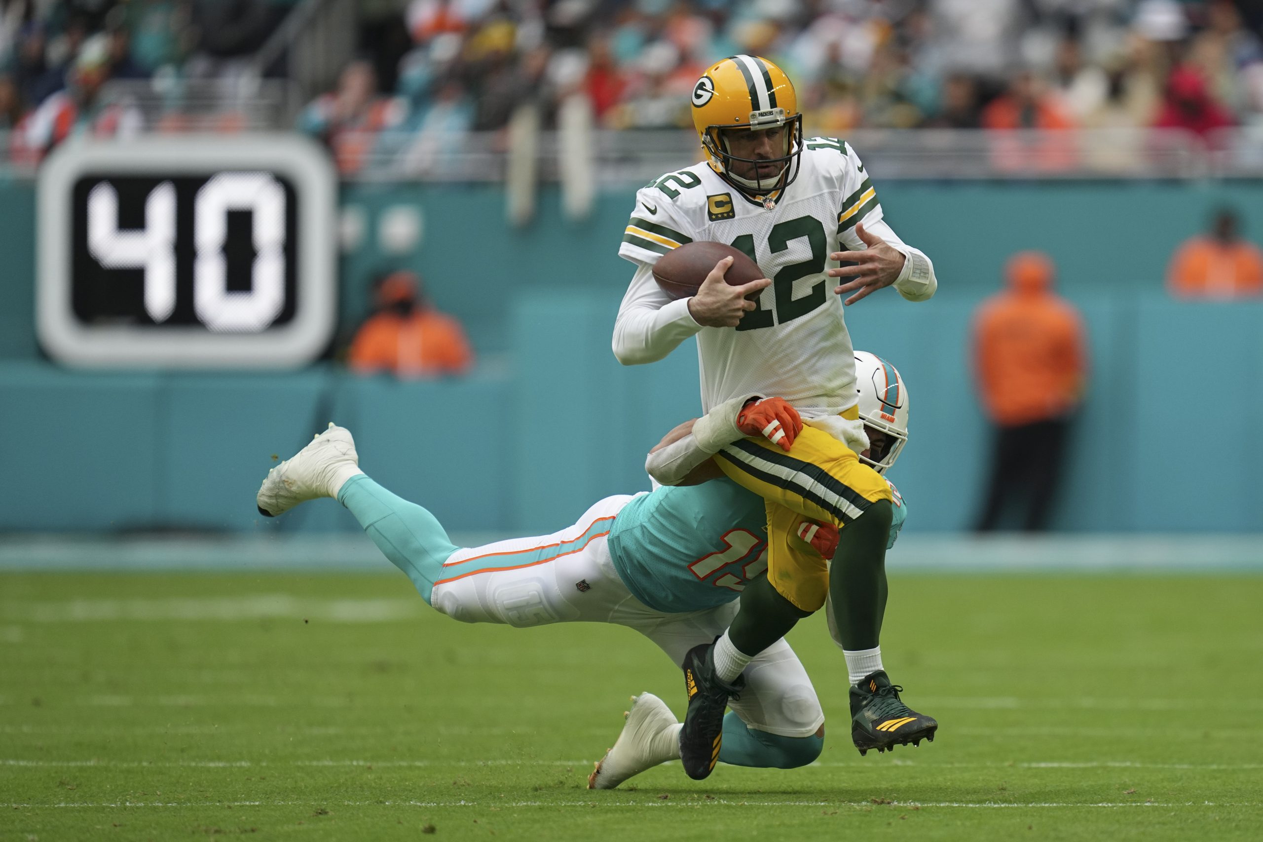 Green Bay Packers quarterback Aaron Rodgers (12) runs through a tackle by Miami Dolphins linebacker Jaelan Phillips (15) as he runs with the ball during the first half of an NFL football game, Sunday, Dec. 25, 2022, in Miami Gardens, Fla. (AP Photo/Jim Rassol)