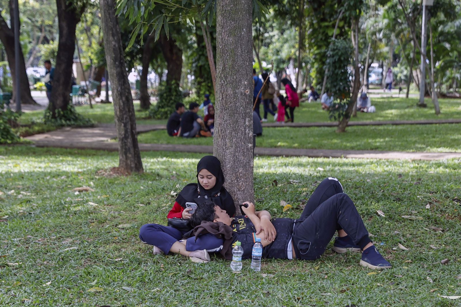 epa10347464 A couple sits on the grass at a public park in Jakarta, Indonesia, 04 December 2022. A new criminal law that will punish sex before marriage with imprisonment is expected to be passed by Indonesia's parliament this month.  EPA/MAST IRHAM