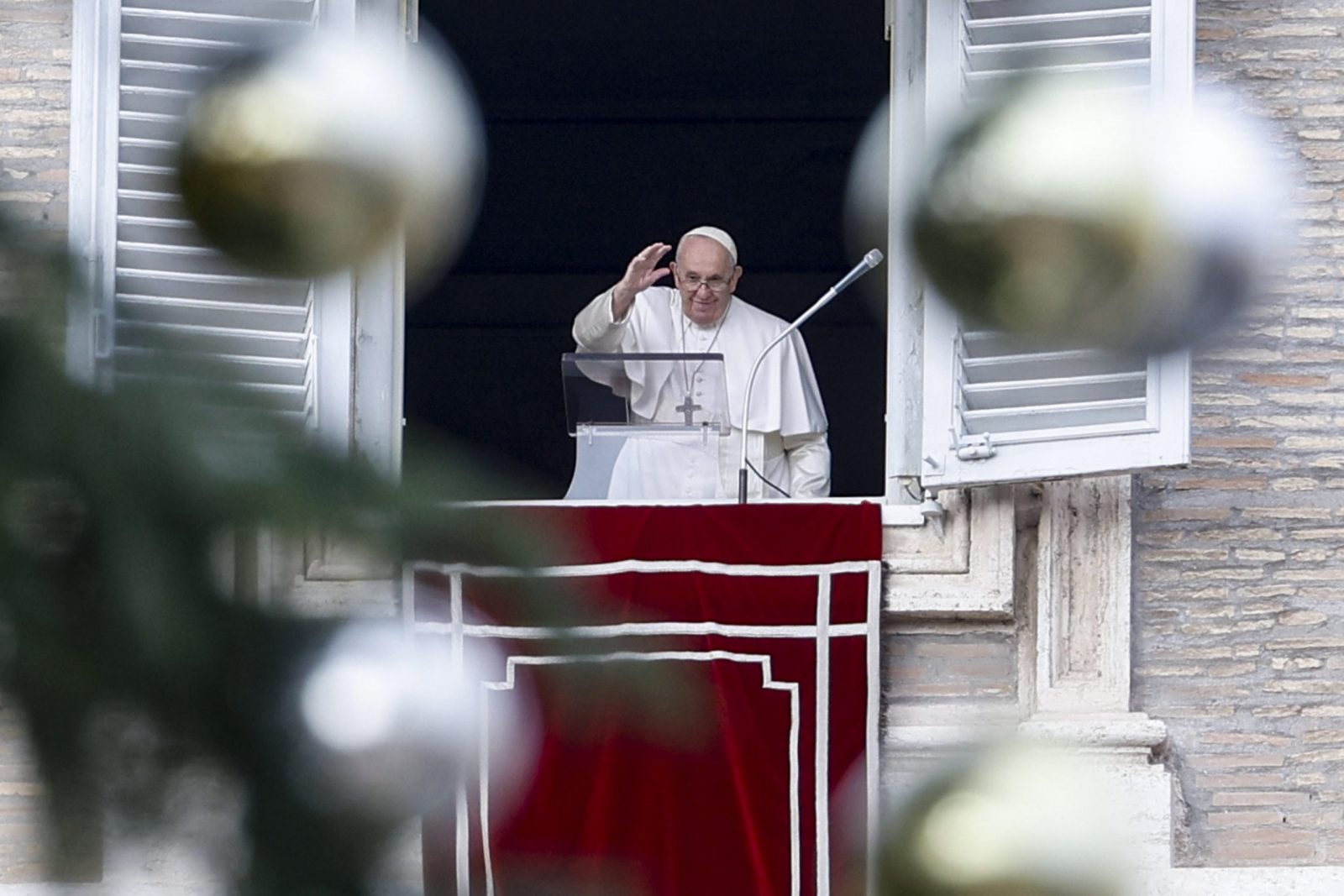 epa10354810 Pope Francis (C) is framed by the branches and decorations of a huge Christmas tree on St. Peter's Square as he delivers the Angelus prayer from a window of his rooms at the Apostolic Palace, Vatican City, 08 December 2022.  EPA/FABIO FRUSTACI