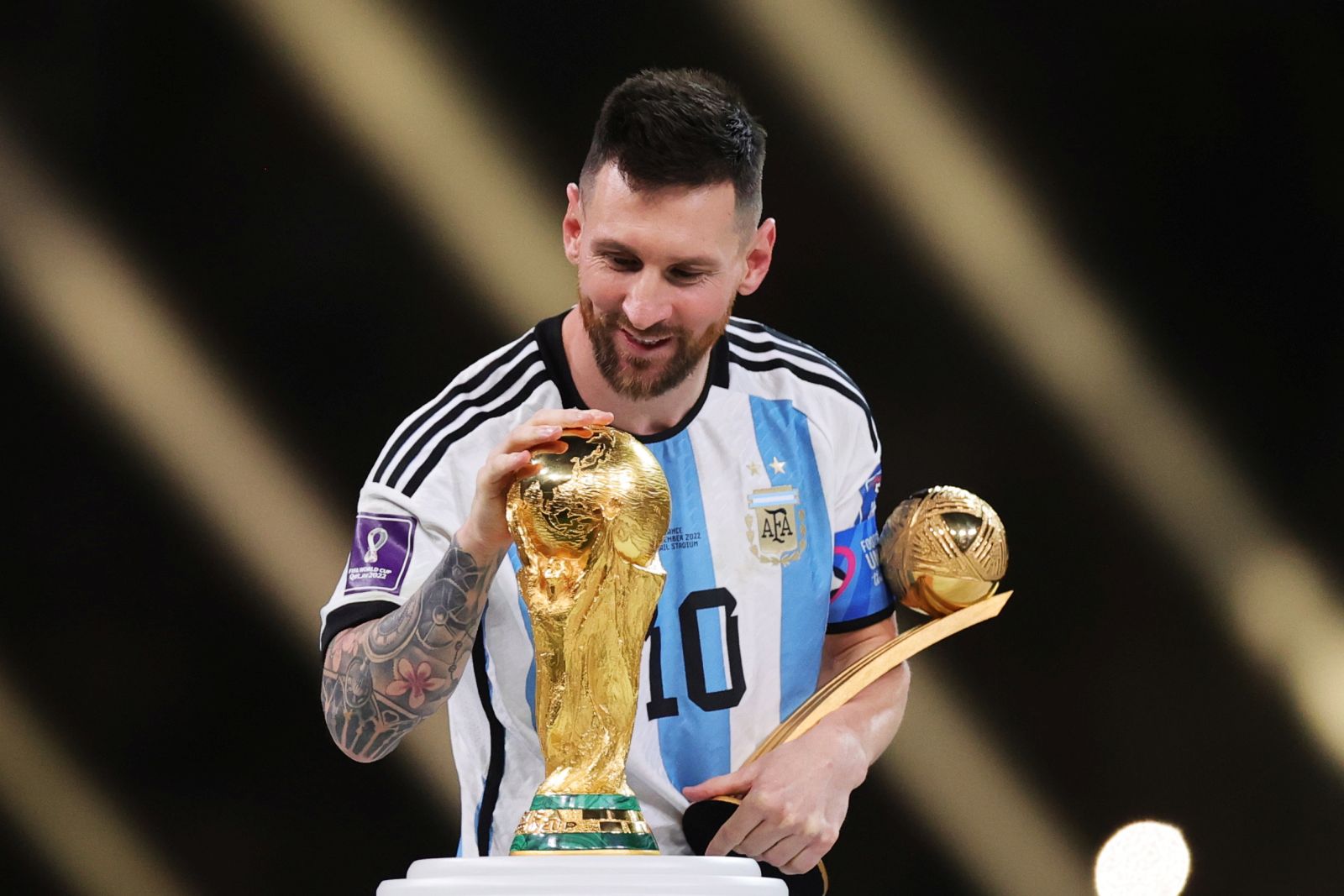epa10373265 Lionel Messi of Argentina touches the World Cup trophy as he passes it after winning the golden ball award during the awards ceremony after the FIFA World Cup 2022 Final between Argentina and France at Lusail stadium, Lusail, Qatar, 18 December 2022.  EPA/Friedemann Vogel