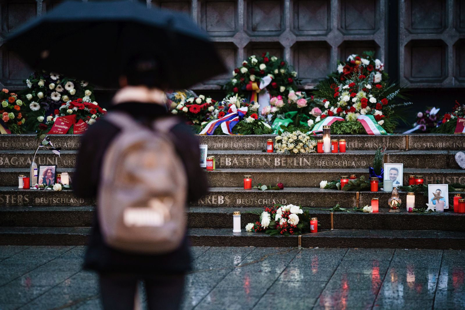 epa10373997 A passer-by with an umbrella stands in front of the memorial of the terror attack, prior to a commemoration event on the 6th anniversary of the terror attack on the Breitscheidplatz square Christmas market in Berlin, Germany, 19 December 2022. During a terror attack on Breitscheidplatz square on 19 December 2016, 12 people were killed when a truck plowed through the Christmas market.  EPA/CLEMENS BILAN