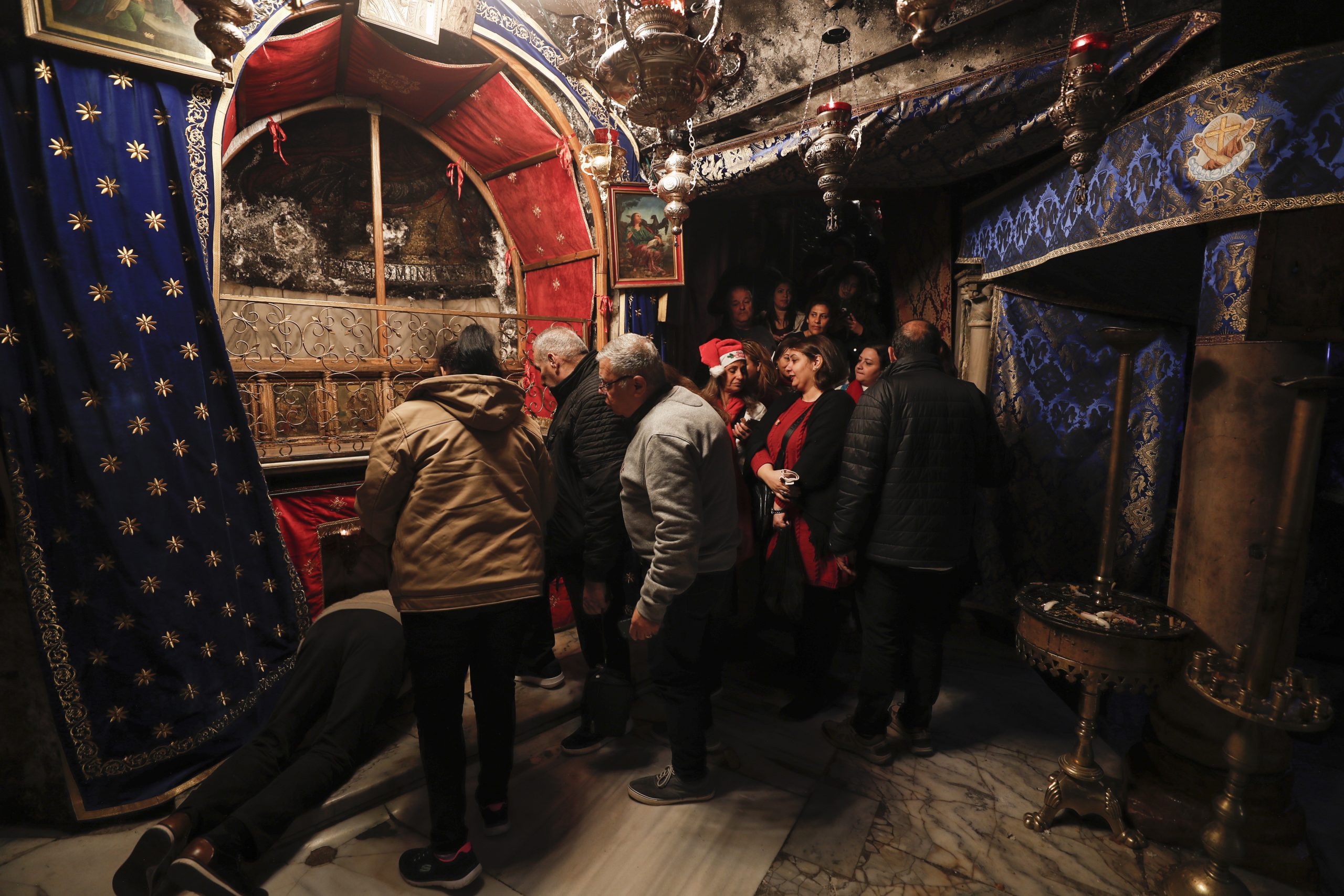 epa10377245 Christian pilgrims pray at the Grotto in the Church of Nativity ahead of Christmas, in Bethlehem, West Bank, 23 December 2022, Church of the Nativity is one of the oldest continuously operating churches worldwide. The structure is built over the cave that tradition marks as the birthplace of Christ, and it is considered sacred by followers of Christianity.  EPA/ATEF SAFADI