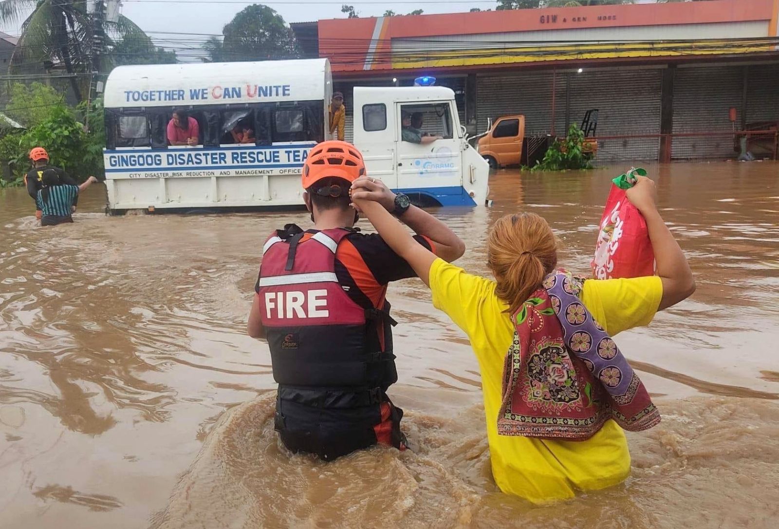 epa10378471 A handout photo made available by the Bureau of Fire Protection (BFP) shows a fire rescue personnel holding a resident on a flooded street on Christmas day in Gingoog city, Misamis Oriental province, Philippines, 25 December 2022 (issued on 26 December 2022). Intense rain brought by a weather occurrence called 'Shear line' caused flooding in southern Philippines that resulted in the death of at least seven villagers.  EPA/BFP HANDOUT BEST QUALITY AVAILABLE HANDOUT EDITORIAL USE ONLY/NO SALES
