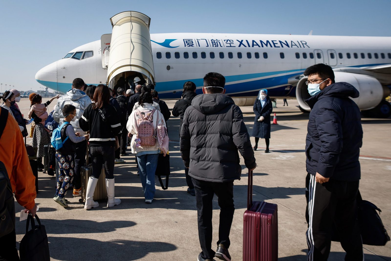 epa10378446 Passengers bound for Beijing board an airplane at the Xiamen Gaoqi International Airport in Xiamen, Fujian province, China, 26 December 2022. People from China's two biggest cities; Beijing and Shanghai have returned to work as the country's medical workers continue to battle a surge in Covid-19 with millions of new cases.  EPA/MARK R. CRISTINO