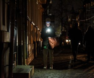 epa10379408 A woman uses her smartphone on the street while the lights are switched off in Kyiv, Ukraine, 27 December 2022. Russian troops on 24 February entered Ukrainian territory, starting a conflict that has provoked destruction and a humanitarian crisis.  EPA/OLEG PETRASYUK