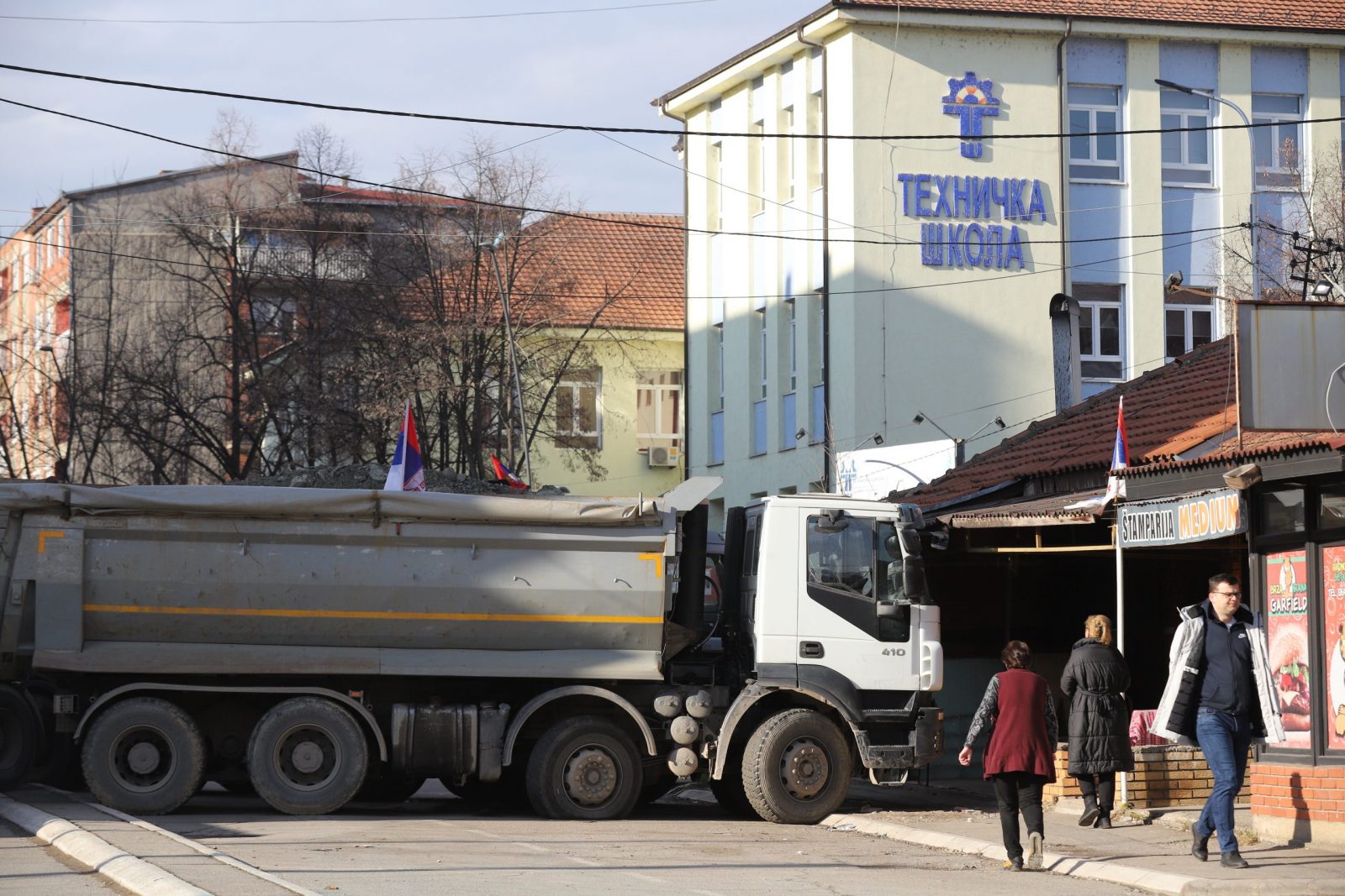 epa10381398 Residents walk past trucks blocking the road in the northern part of Mitrovica, Kosovo, 29 December 2022. Serbian President Aleksandar Vucic declared that ethnic Serbs will start removing barricades blocking roads in the north of Kosovo since 11 December 2022, in a move that deescalates tensions that triggered fears of new clashes in the troubled region.  EPA/STR