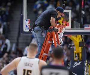 A worker uses a level to check the rim after it was bent by a dunk by Boston Celtics center Robert Williams III in the second half of an NBA basketball game against the Denver Nuggets, Sunday, Jan. 1, 2023, in Denver. (AP Photo/David Zalubowski)