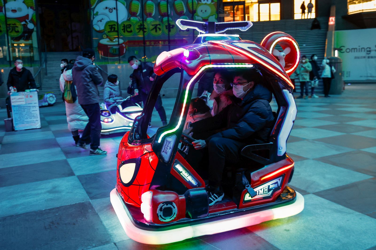 epa10383803 A family rides a Spiderman themed vehicle at a shopping district amid the COVID-19 outbreak during New Year's Eve in Beijing, China, 31 December 2022. The World Health Organization (WHO) has urged Chinese officials to share real-time information on COVID-19 as infections continue to surge after restrictions have been lifted around the country.  EPA/MARK R. CRISTINO