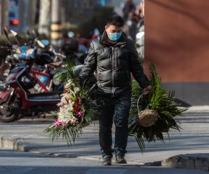 epa10388598 A man carries flowers in front of the funeral home, in Shanghai, China, 04 January 2023. Mortuaries and funeral homes in China have been overwhelmed amid the recent outbreak of COVID-19 pandemic with numerous bodies awaiting cremation. There have been an estimated 9,000 deaths and 1.8 million infections per day across China, according to the data released by Health risk analysis firm Airfinity on 29 December 2022.  EPA/ALEX PLAVEVSKI