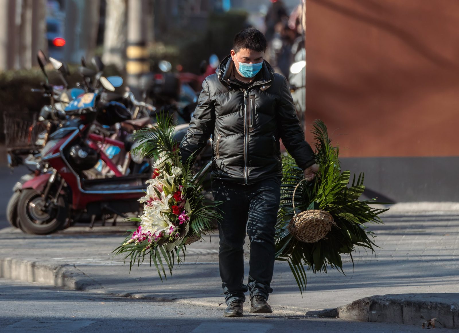 epa10388598 A man carries flowers in front of the funeral home, in Shanghai, China, 04 January 2023. Mortuaries and funeral homes in China have been overwhelmed amid the recent outbreak of COVID-19 pandemic with numerous bodies awaiting cremation. There have been an estimated 9,000 deaths and 1.8 million infections per day across China, according to the data released by Health risk analysis firm Airfinity on 29 December 2022.  EPA/ALEX PLAVEVSKI