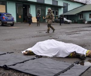 epa10392450 A territorial defense soldier walks past the covered body of a Ukrainian rescuer who was killed in a  shelling of a fire station in Kherson, Ukraine, 06 January 2022. Russian President Putin the previous day declared a unilateral ceasefire for 06 and 07 January for the Christmas celebrations. Russian and most Ukrainian believers celebrate the Orthodox Christmas Day according to the old Julian calendar on 07 January.  EPA/IVAN ANTYPENKO