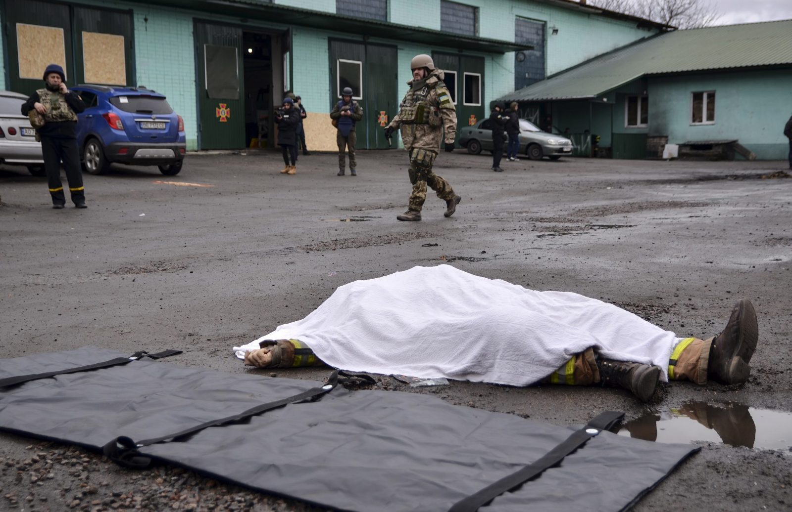 epa10392450 A territorial defense soldier walks past the covered body of a Ukrainian rescuer who was killed in a  shelling of a fire station in Kherson, Ukraine, 06 January 2022. Russian President Putin the previous day declared a unilateral ceasefire for 06 and 07 January for the Christmas celebrations. Russian and most Ukrainian believers celebrate the Orthodox Christmas Day according to the old Julian calendar on 07 January.  EPA/IVAN ANTYPENKO