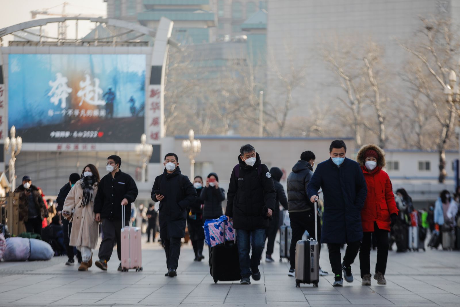 epa10397598 Passengers wearing face masks walk with their luggage in front of the Beijing Railway Station in Beijing, China, 10 January 2023. Chinese passengers are travelling domestically as the nation's most important holiday season kicked off, after the end of China's zero-COVID policy that was in place for three years. Some 34 million trips across the country were made by road, railway, water or air on 07 January on the first day of the Lunar New Year travel rush, according to the data released by the Ministry of Transport.  EPA/WU HAO