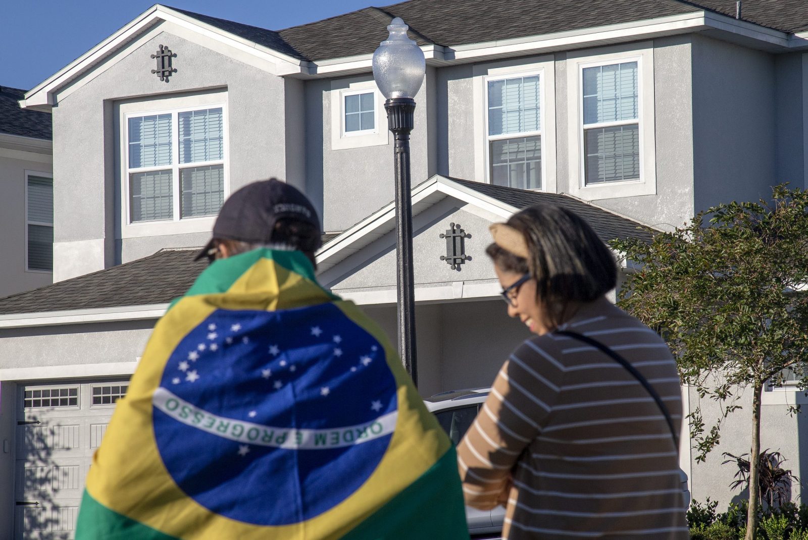 epa10401534 People stand in front of the house at the Encore Resort Homes, where former Brazil president Jair Bolsonaro is staying, in Reunion, Florida, USA, 12 January 2023. US Lawmakers called US President Joe Biden to extradite Bolsonaro back to his country from Florida. Bolsonaro has been staying in Central Florida, near Orlando, as his supporters protest in Brazil.  EPA/CRISTOBAL HERRERA-ULASHKEVICH