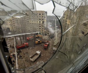 epa10407133 A view taken through the broken glass of a window overlooking the site of a damaged residential building as rescue works continue, in Dnipro, southeastern Ukraine, 15 January 2023, amid Russia's invasion. At least 25 people died, including one child, 73 other were injured, including 13 children, and 43 reports of missing persons were received, after a rocket hit a nine-story building in Dnipro on 14 January, the State Emergency Service (SES) of Ukraine said in a statement. Russian troops entered Ukraine on 24 February 2022 starting a conflict that has provoked destruction and a humanitarian crisis.  EPA/OLEG PERTASYUK