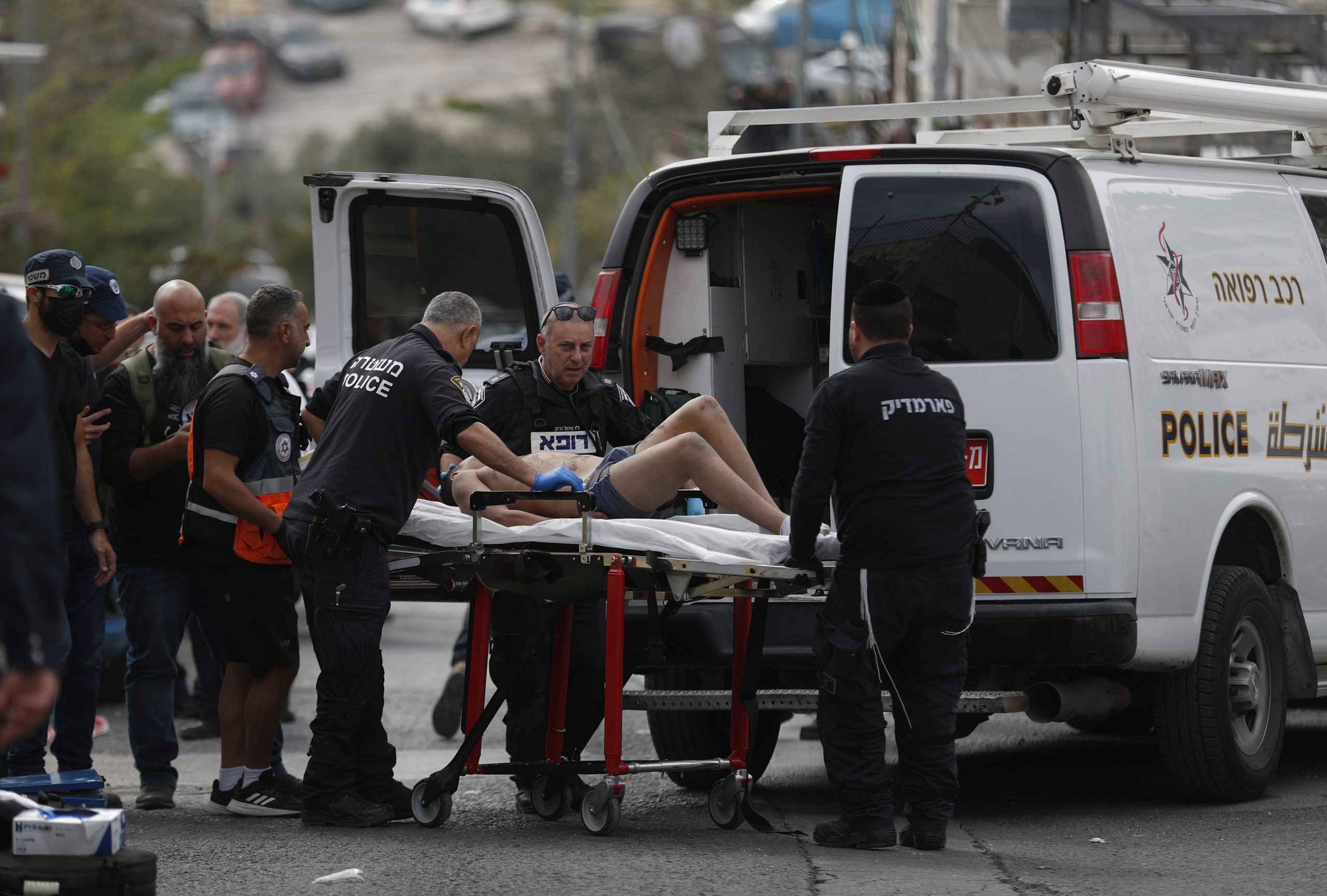 epa10435397 A man on a stretcher, suspected to be attacker, is brought to a Police van by Israeli police officers at the scene of a shooting near the Old City in Jerusalem, 28 January 2023, a day after deadly attack on synagogue. According to Israeli police and paramedic services, two men are wounded after a new shooting attack in Jerusalem. Seven people were killed and at least three other injured in a shooting attack at a synagogue in Jerusalem on 27 January.  EPA/ATEF SAFADI