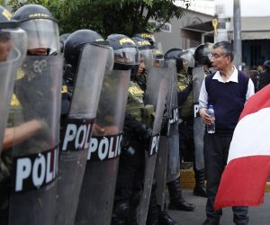 epa10419302 A man with a Peruvian flag walks in front of members of the Police during a new anti-government march in Lima, Peru, 20 January 2023. The anti-government demonstrations led to new clashes with the security forces and caused 'severe damage' to the infrastructure in the historic center of the Peruvian capital, official sources reported. The protests brought together thousands of people for the second day in a row, many of them coming from the southern regions of Peru and, after a peaceful start, led to clashes with police officers, who fired tear gas on various streets.  EPA/Hugo Curotto