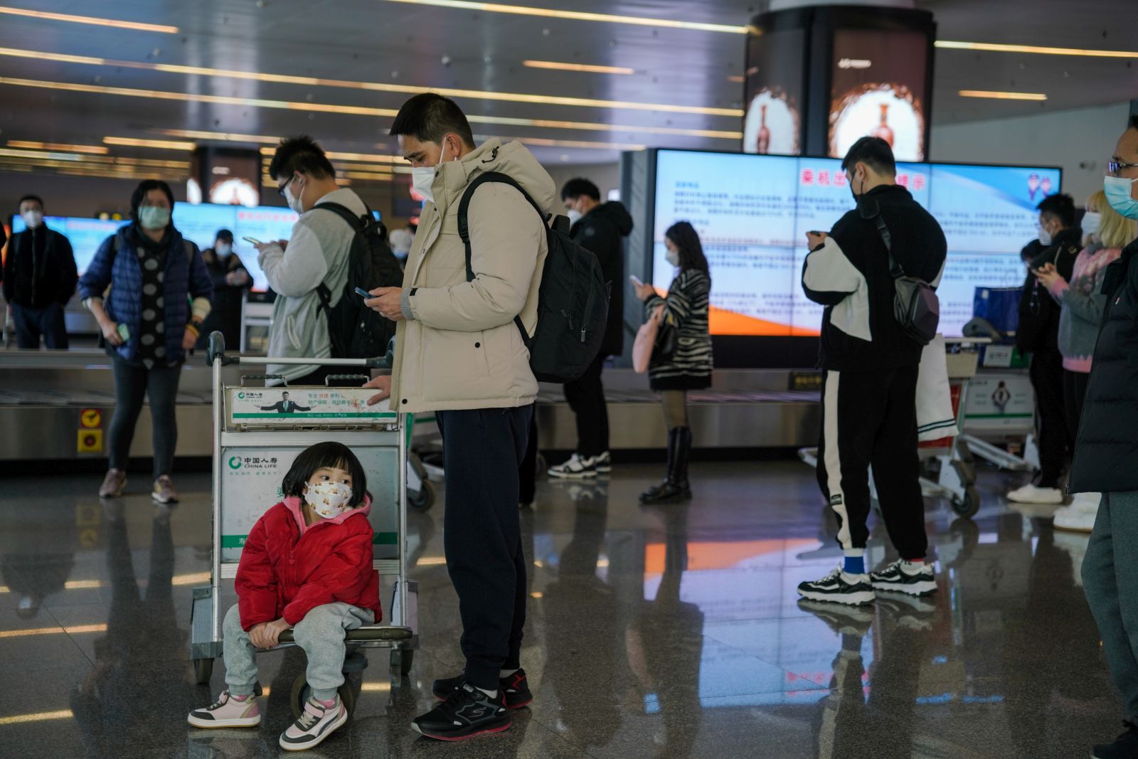 epa10412499 Passengers wearing face masks walk with their luggage at Nanning Wuxu International Airport in Nanning, Guangxi Zhuang Autonomous Region, China, 18 January 2023. Chinese passengers are traveling domestically as the country’s most important holiday season kicked off, after the lifting of its zero-Covid policy. Some 34 million trips across the country were made by road, railway, water or air on 07 January alone, the first day of the Lunar New Year travel rush, according to the data released by the Ministry of Transport.  EPA/WU HAO