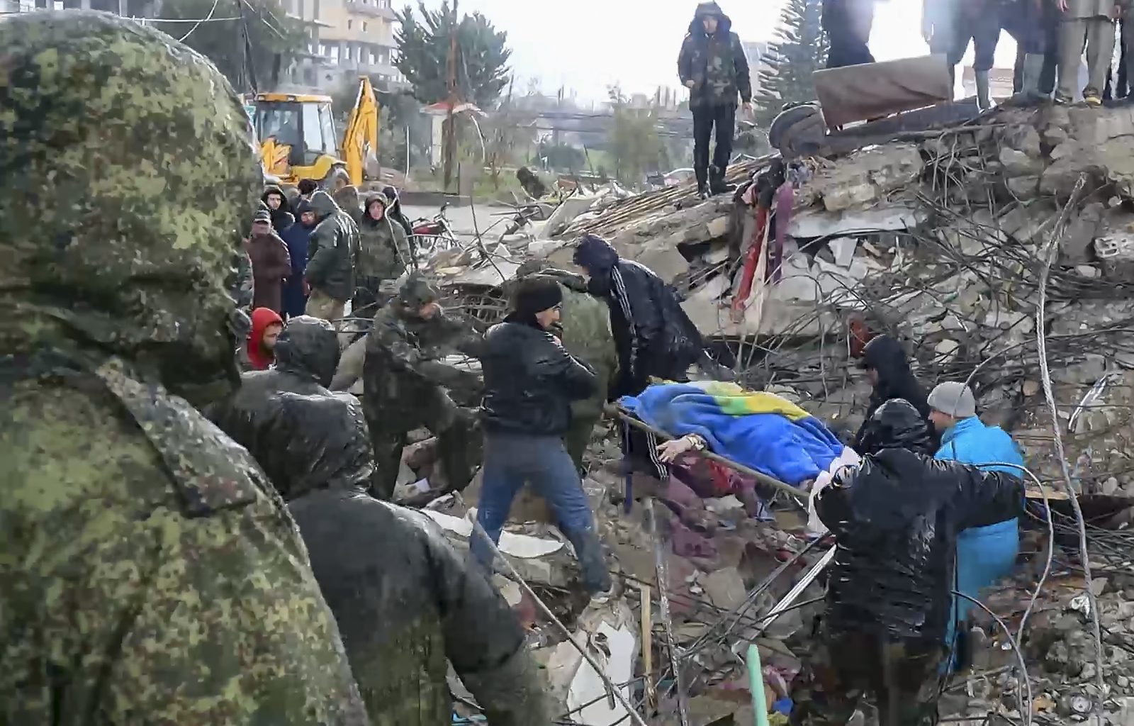 epa10452104 A still image taken from a handout video provided by the Russian Defence Ministry Press-Service on 07 February 2023 shows Syrian and Russian servicemen helping locals carrying the body of a victim found at the site of a collapsed building after a major earthquake in Latakia, Syria. More than 4,000 people were killed and thousands more injured after a major 7.8 magnitude earthquake struck southern Turkey and northern Syria on 06 February. Authorities fear the death toll will keep climbing as rescuers look for survivors across the region.  EPA/RUSSIAN DEFENCE MINISTRY PRESS SERVICE HANDOUT -- BEST QUALITY AVAILABLE -- MANDATORY CREDIT -- HANDOUT EDITORIAL USE ONLY/NO SALES