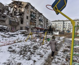epa10488305 A woman walks past a damaged building in Sviatohirsk, Donetsk region, eastern Ukraine, 24 February 2023. Russian troops entered Ukrainian territory on 24 February 2022, starting a conflict that has provoked destruction and a humanitarian crisis. One year on, fighting continues in many parts of the country.  EPA/OLEG PETRASYUK