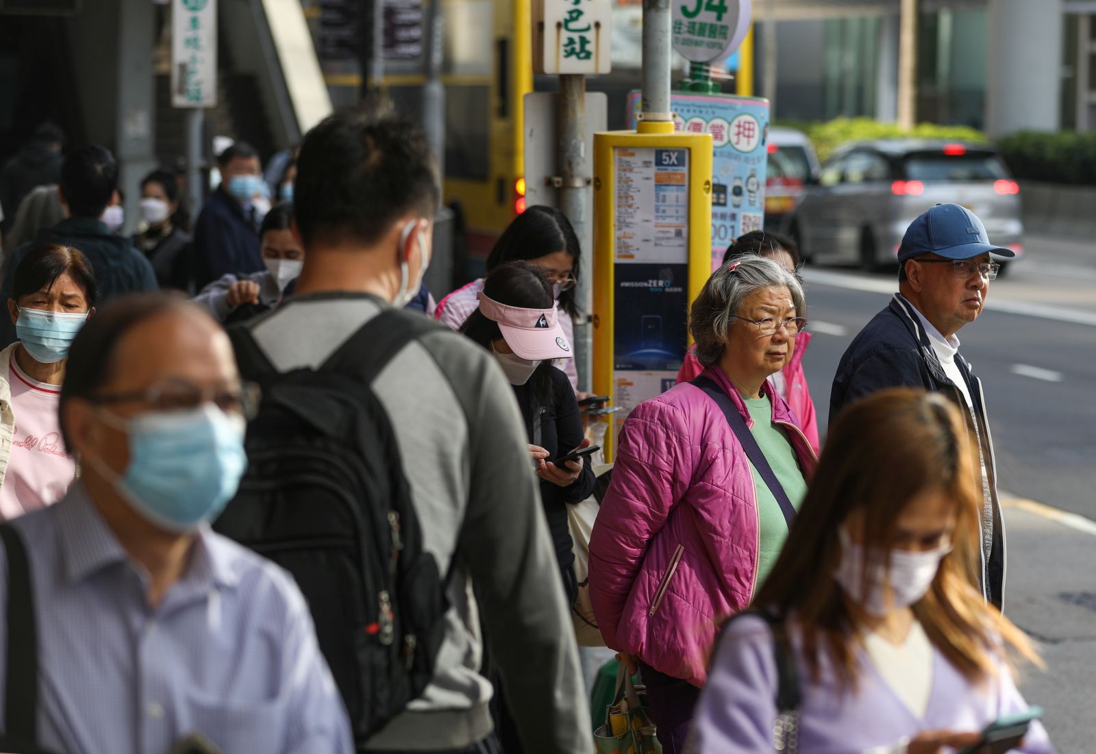 epa10496448 Commuters, with some of them still wearing face masks, wait at a bus stop in Hong Kong, China, 01 March 2023. With the end of the mask mandate on 01 March 2023, residents and visitors to Hong Kong will not have to wear face masks any more for all indoor and outdoor places after almost three years.  EPA/JEROME FAVRE