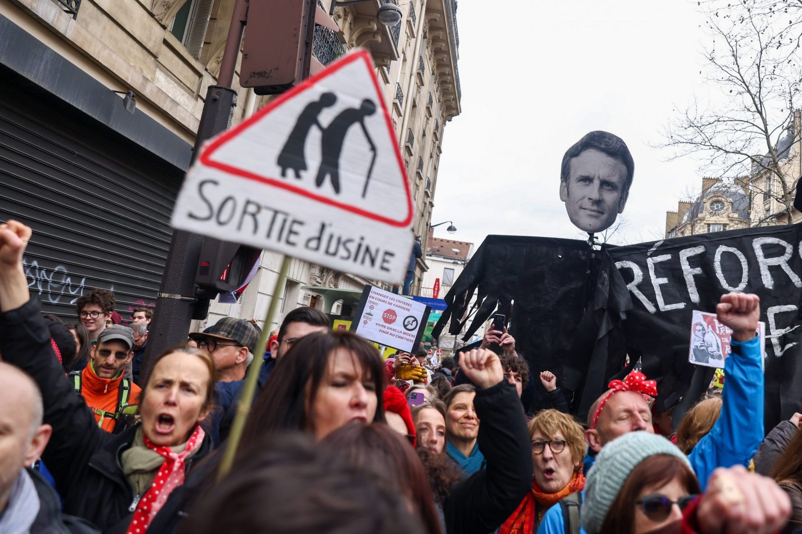 epa10507561 Protesters hold a banner showing French President Macron's face, during a protest against the French government's planned reform of the pension system, in Paris, France, 07 March 2023. The French government plans to delay the minimum retirement age from 62 to 64, until 2030.  EPA/MOHAMMED BADRA