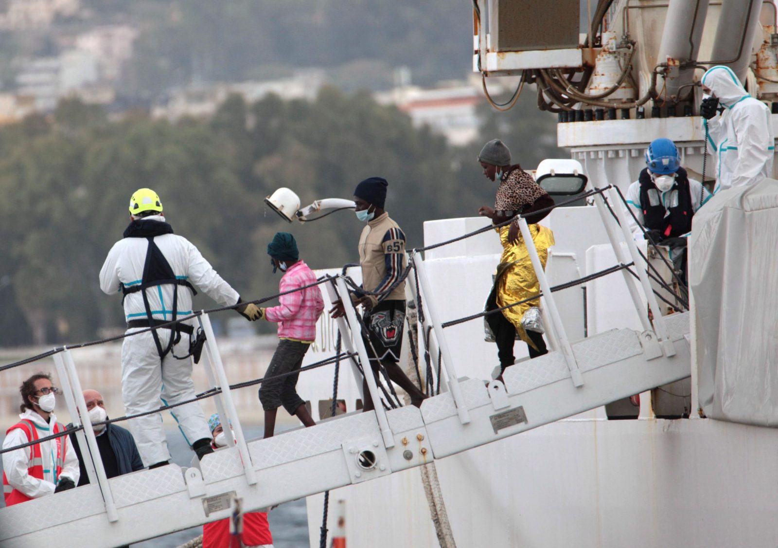 epa10514926 Social and health workers carry out the disembarkation operations of the first migrants rescued at sea, at a port in Reggio Calabria, southern Italy, 11 March 2023.  EPA/MARCO COSTANTINO