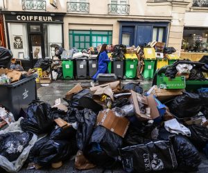 epa10522067 People pass by next to garbage cans overflowing with trash in Paris, France, 14 March 2023. Garbage collectors have joined the massive strikes in France against the government's pension reform plans, piling the streets of the French capital in the meantime with thousands of tonnes of garbage.  EPA/Mohammed Badra  HANDOUT EDITORIAL USE ONLY/NO SALES