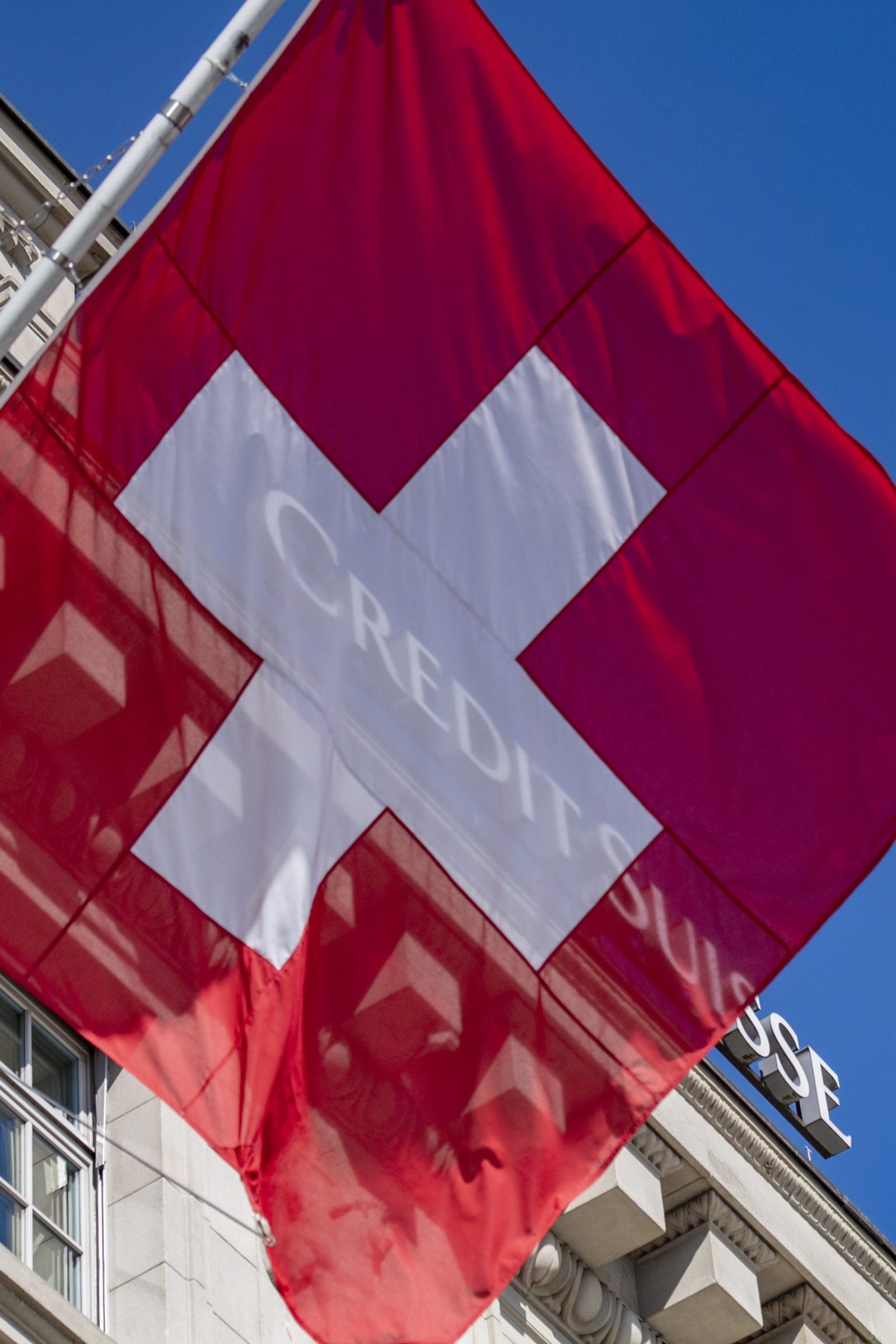 epa10526767 A Swiss national flag flies in front of the logo of Swiss bank Credit Suisse CS in Lucerne, Switzerland, 16 March 2023. Credit Suisse is borrowing up to 50 billion francs (50.8 billion euros) from the Swiss National Bank (SNB), according to a statement on 16 March 2023. This is intended to strengthen the group, whose shares have crashed on the stock exchange.  EPA/URS FLUEELER