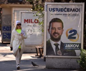 epa10528198 A woman walks past campaign billboards of the Presidential candidates Milo Djukanovic and Jakov Milatovic ahead of the upcoming Presidential elections in Podgorica, Montenegro, 17 March 2023. Presidential elections are due to be held in Montenegro on 19 March 2023.  EPA/BORIS PEJOVIC
