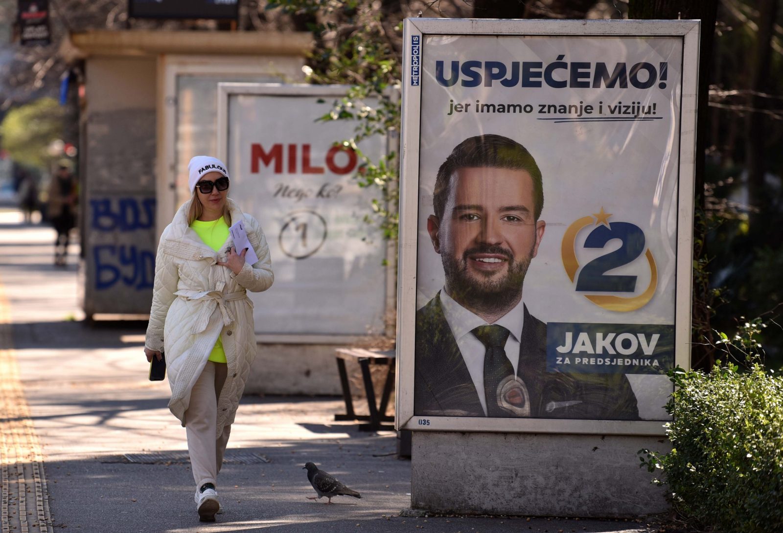 epa10528198 A woman walks past campaign billboards of the Presidential candidates Milo Djukanovic and Jakov Milatovic ahead of the upcoming Presidential elections in Podgorica, Montenegro, 17 March 2023. Presidential elections are due to be held in Montenegro on 19 March 2023.  EPA/BORIS PEJOVIC