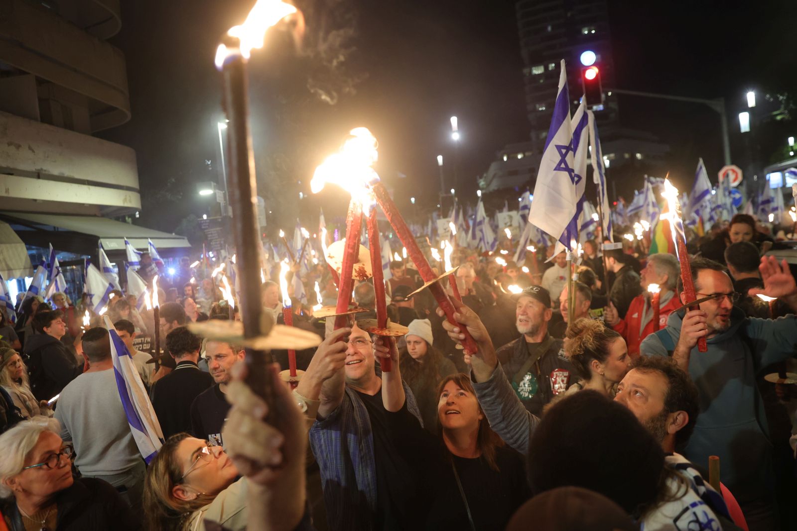 epa10530457 People light torches during a protest against the government's justice system reform plans in Tel Aviv, Israel, 18 March 2023. Nationwide protests against the government's judicial reform plans are being held for eleven weeks in a row. Israel's parliament passed a draft law limiting the power of the Israeli Supreme Court in a first reading on 14 March.  EPA/ABIR SULTAN