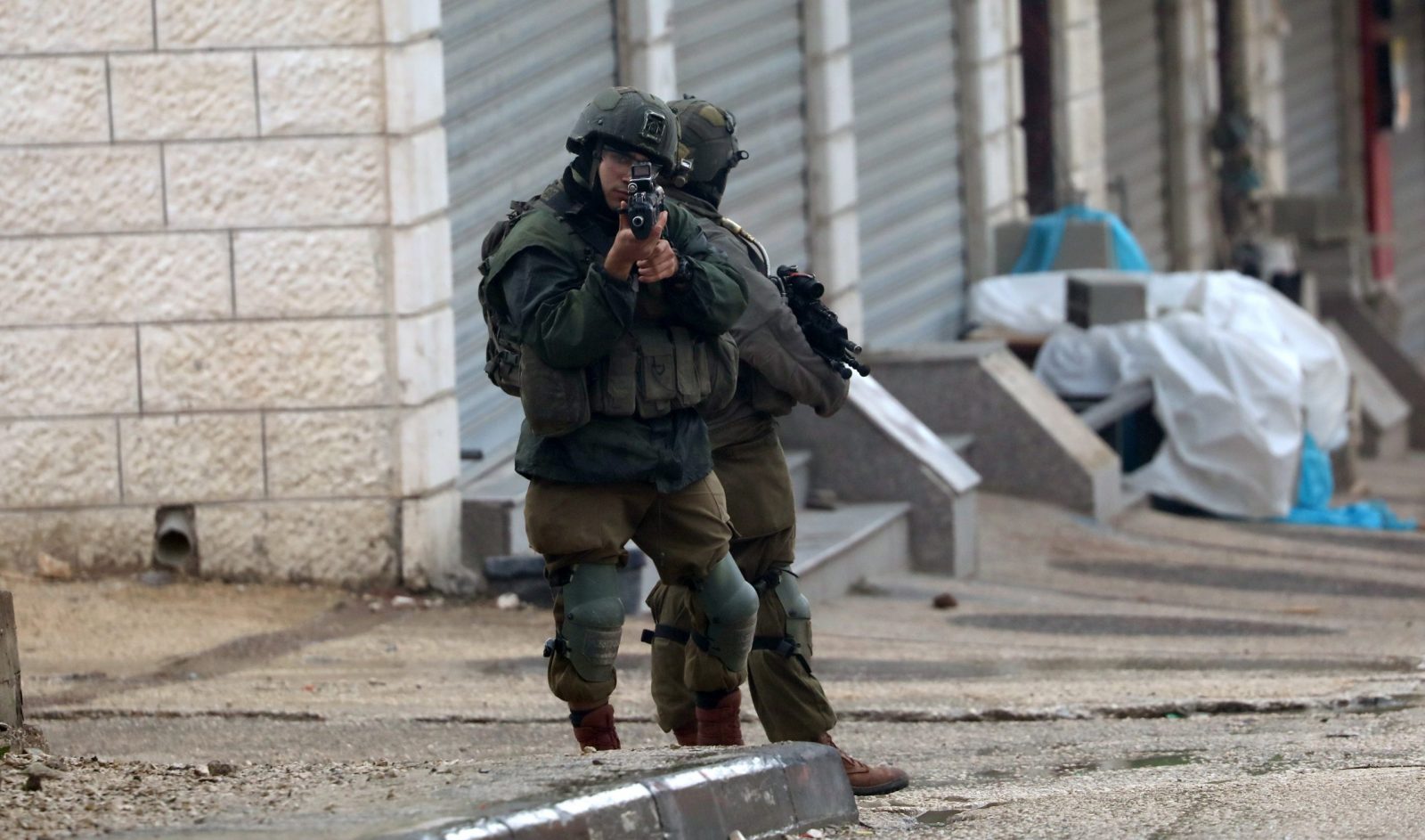 epa10532437 Israeli soldiers stop a Palestinian man in the area following a shooting attack in the West Bank town of Hawara, near the city of Nablus, 19 March 2023. The Israeli Army said on 19  March that they blocked the area after an attacker opened fire towards an Israeli vehicle. Israeli officials said that two Israelis were wounded in the shooting.  EPA/ALAA BADARNEH
