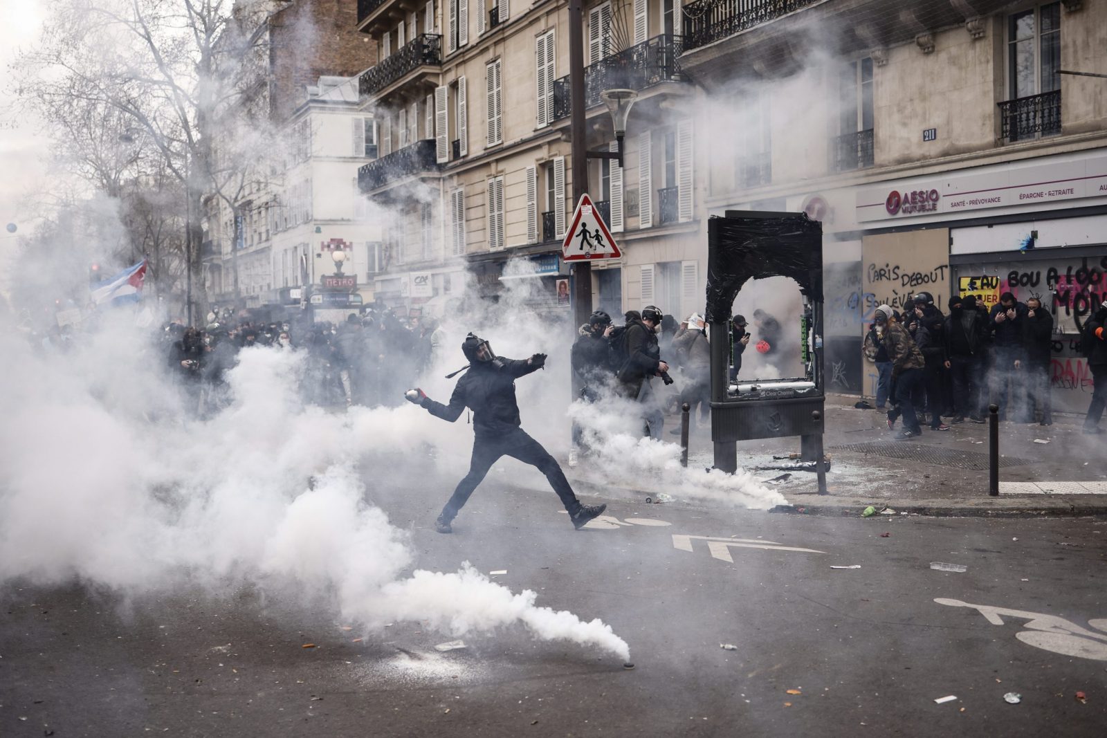 epa10547325 A protester throws a tear gas during demonstration against government pension reform in Paris, France, 28 March 2023. France faces an ongoing national strike against the government's pensions reform after Prime Minister Elisabeth Borne on 16 March announced the use of article 49 paragraph 3 (49.3) of the Constitution of France to have the text on the controversial pension reform law to be definitively adopted without a vote.  EPA/YOAN VALAT