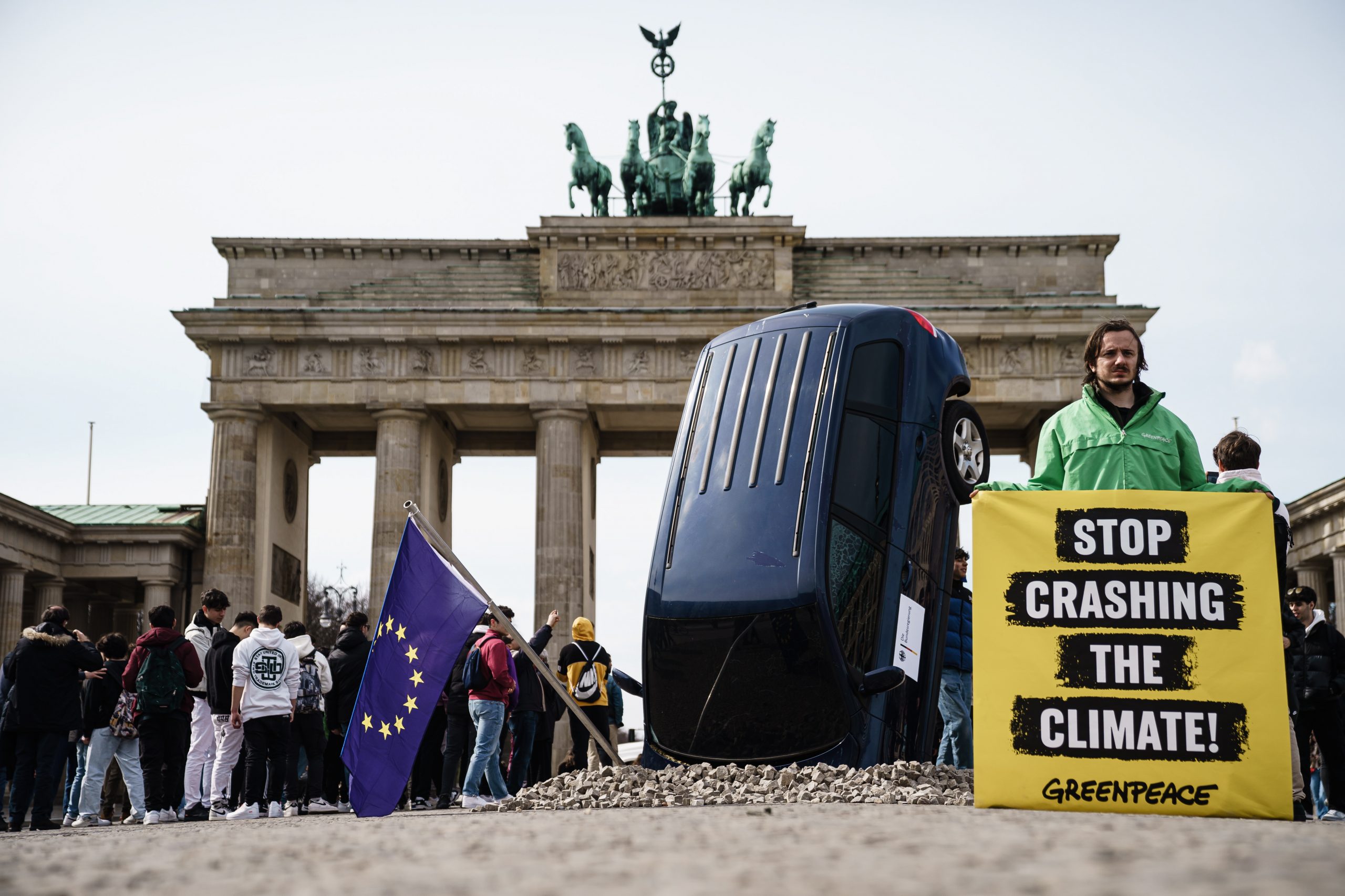 epa10536840 A Greenpeace installation shows an SUV that crashed into the ground before the Brandenburg Gate, as part of a protest against the German blockade of a European phase-out of combustion engines, in Berlin, Germany, 22 March 2023.  EPA/CLEMENS BILAN