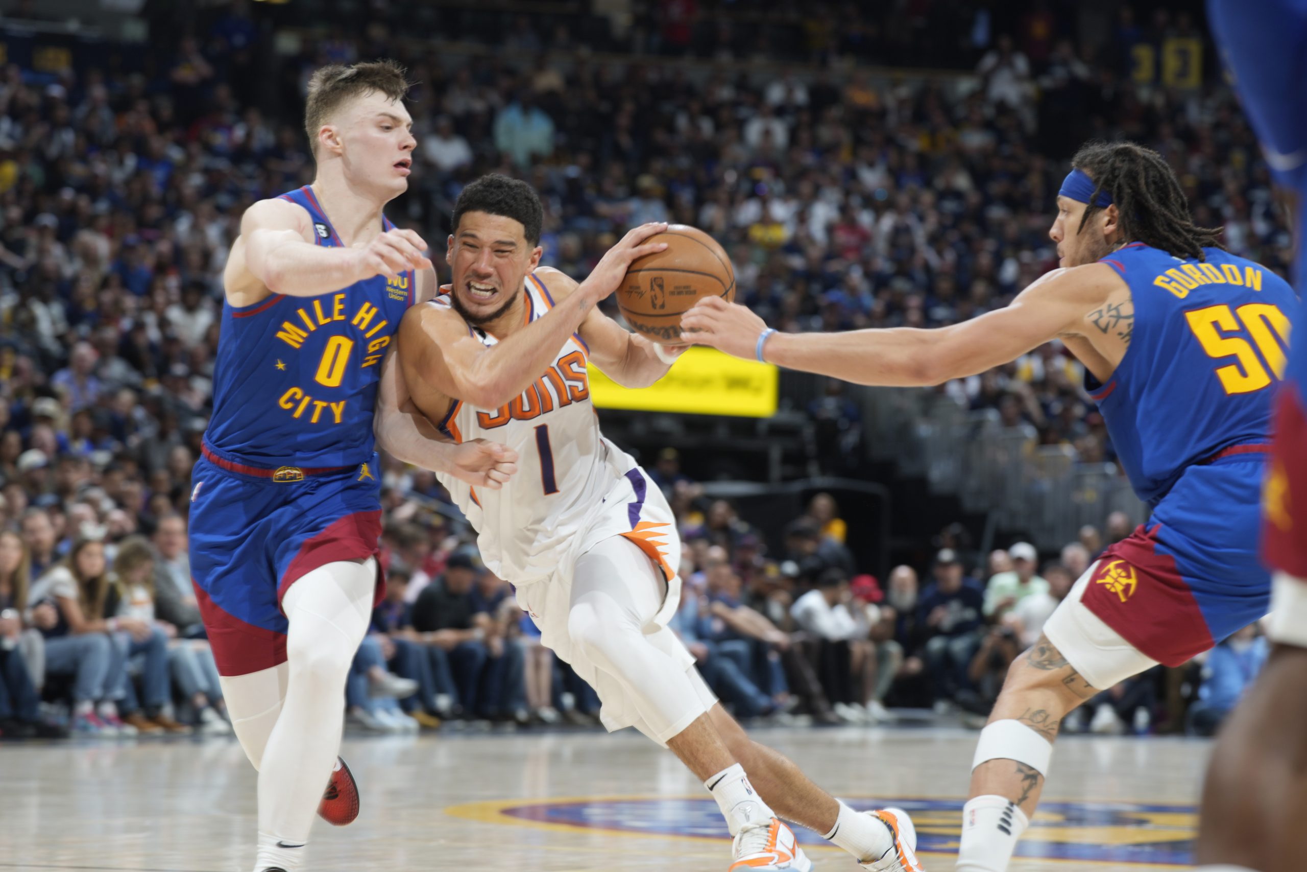 Phoenix Suns guard Devin Booker, center, drives the lane as Denver Nuggets guard Christian Braun, left, and forward Aaron Gordon defend in the second half of Game 1 of an NBA second-round basketball series Saturday, April 29, 2023, in Denver. (AP Photo/David Zalubowski)