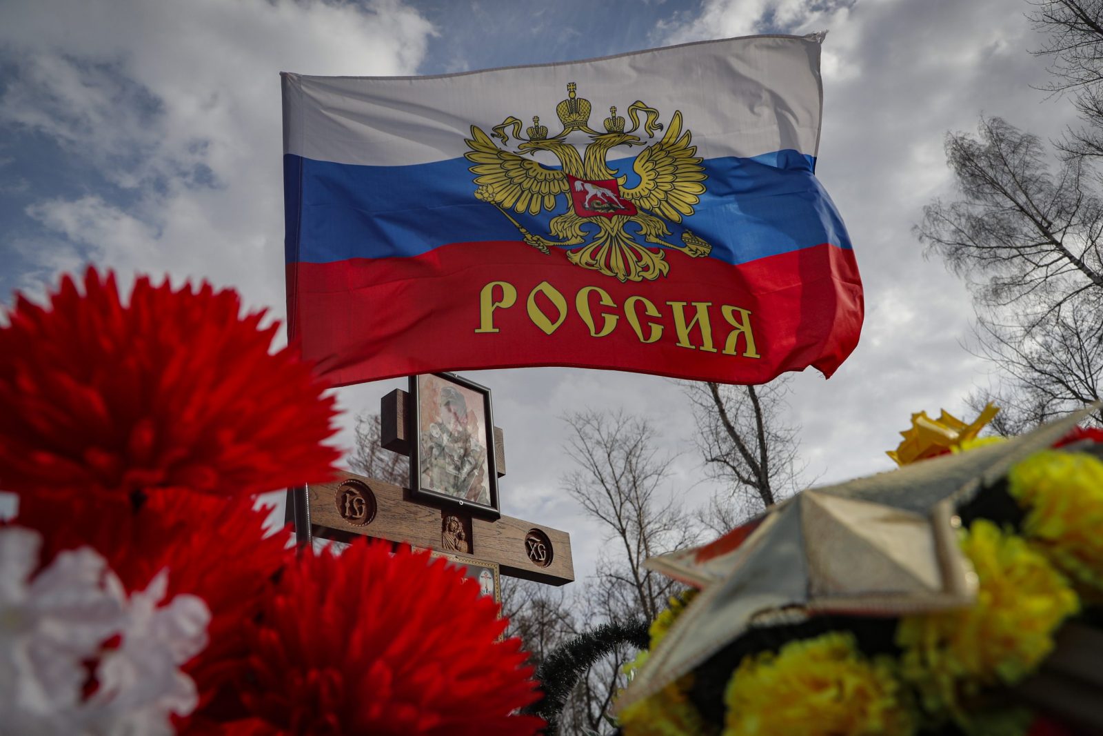 epa10561989 A Russia flag flies on a flower decorated garve of a Russian serviceman on the cemetery near the town Yefremov, Tula region, Russia, 06 April 2023.  EPA/MAXIM SHIPENKOV