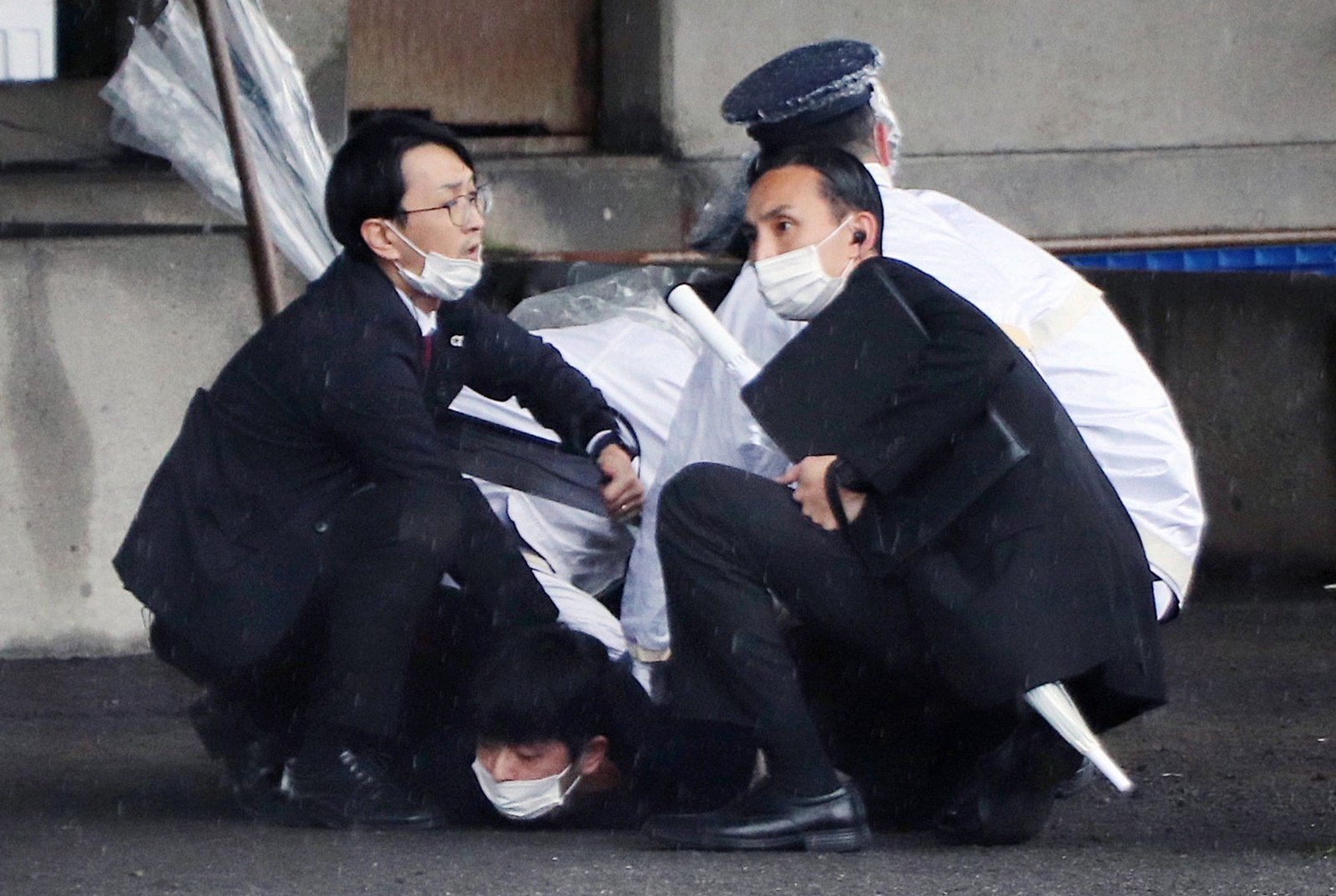 epa10573225 Police officers arrest a man suspected to have thrown explosives as Japanese Prime Minister Fumio Kishida was about to make a stump speech at a fishing port in Wakayama, Wakayama Prefecture, western Japan, 15 April 2023. A loud explosion was heard just before Kishida was set to speak. Kishida was not harmed in the explosion and police forces arrested the suspect believed to have thrown the explosive.  EPA/JIJI PRESS JAPAN OUT EDITORIAL USE ONLY / ALTERNATE CROP