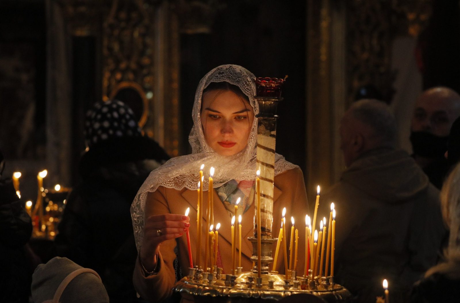 epa10575542 A Ukrainian woman lights a candle as faithful attend an Orthodox Easter mass at St. Volodymyr Cathedral in Kyiv (Kiev), Ukraine, 16 April 2023. Eastern Orthodox Christians worldwide celebrate Easter on 16 April 2023, according to the Julian calendar. Christians celebrate Easter Sunday to mark the resurrection of Jesus Christ from the dead and the foundation of the Christian faith.  EPA/SERGEY DOLZHENKO