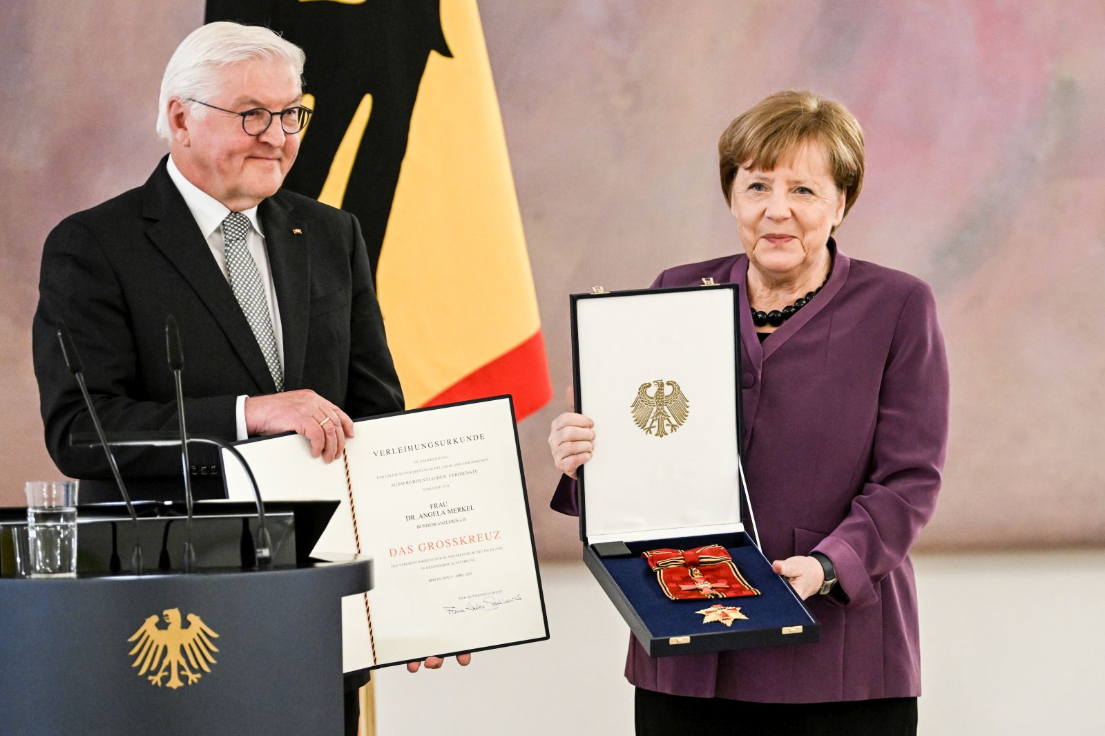 epa10577208 Former German Chancellor Angela Merkel (R) poses with the box after she was awarded the 'Grand Cross of the Order of Merit of the Federal Republic of Germany' by German President Frank-Walter Steinmeier (L) during a ceremony in Berlin, Germany, 17 April 2023.  EPA/FILIP SINGER