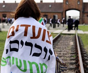 epa10578606 A participant stands on tracks during the ‘March of the Living’ along the 'road of death' from the former Nazi German Auschwitz I camp to Auschwitz II-Birkenau in Oswiecim, Poland, 18 April 2023. The annual march, commemorating the victims of the Holocaust, takes place annually since 1988 at the site of Nazi German concentration and extermination camp Auschwitz-Birkenau. Over 1.1 million people, mostly Jews, lost their lives in Auschwitz death camps during the World War II.  EPA/ZBIGNIEW MEISSNER POLAND OUT