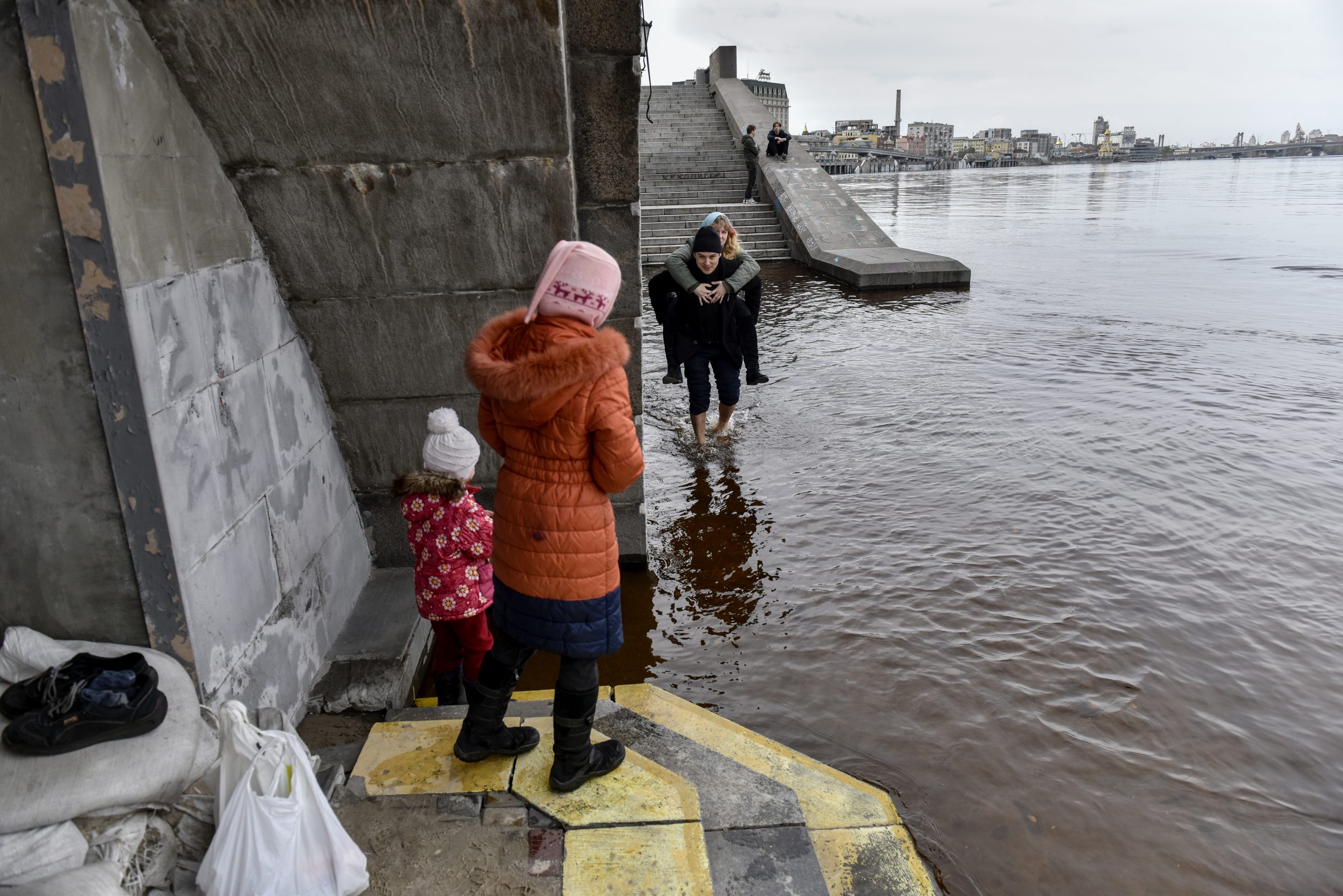 epa10584454 A man carries his wife on his back across a flooded quay amid flooding of the Dnipro River, in Kyiv (Kiev), Ukraine, 21 April 2023, as Russia's invasion of Ukraine continues. According to the Ukrainian Hydrometeorological Center of the State Emergency Service of Ukraine (SES), flood water levels in the Dnipro River within the capital have been declining for several days in a row, with no current flood emergency issued in Kyiv. This year's spring flooding affected several regions across northern and central Ukraine. Russian troops entered Ukraine on 24 February 2022, starting a conflict that has provoked destruction and a humanitarian crisis.  EPA/OLEG PETRASYUK
