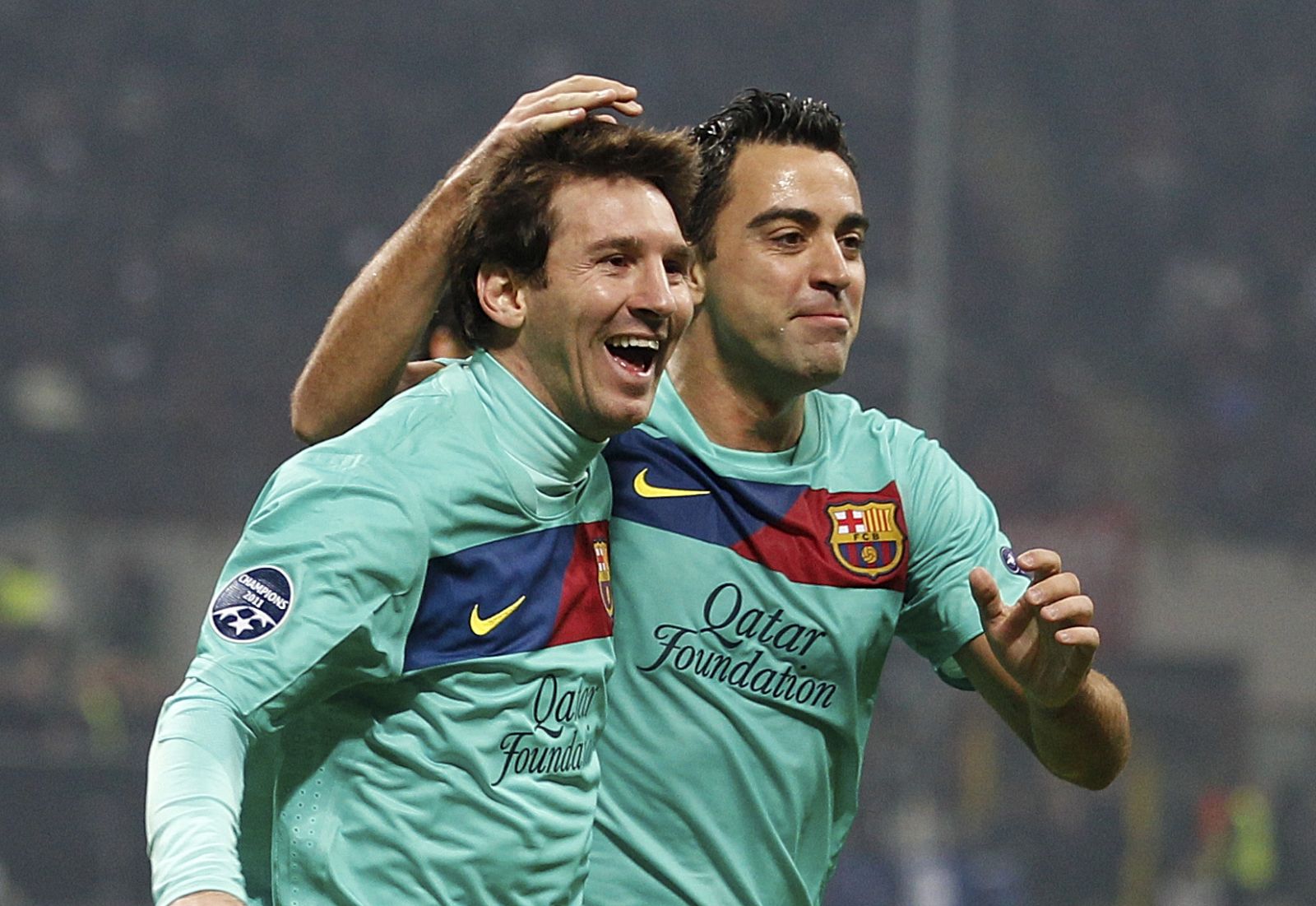 Barcelona forward Lionel Messi, of Argentina, left, celebrates with teammates midfielder Xavi Hernandez after an own goal of AC Milan midfielder Mark Van Bommel, during a Champions League, Group H soccer match between AC Milan and Barcelona at the San Siro stadium in Milan, Italy, Wednesday, Nov.23, 2011. (AP Photo/Luca Bruno)