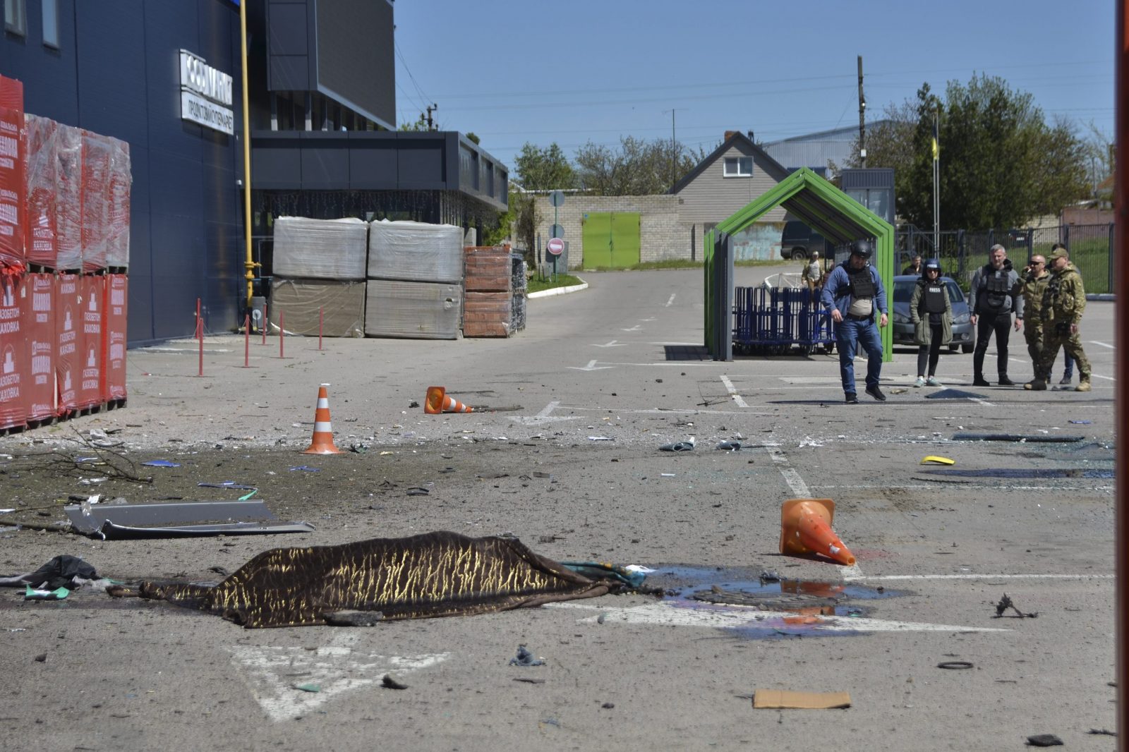 epa10606513 The covered body of a dead person, lies in front of a shelled construction hypermarket in Kherson, Ukraine, 03 May 2023 amid the Russian invasion. Russian troops struck the construction hypermarket, railway station, gas station and residential area of Kherson. At least 16 people were killed and 28 injured by Russian shelling of Kherson region, on 03 May, Roman Mrochko, Head of the Kherson City Military Administration reported.  EPA/IVAN ANTYPENKO